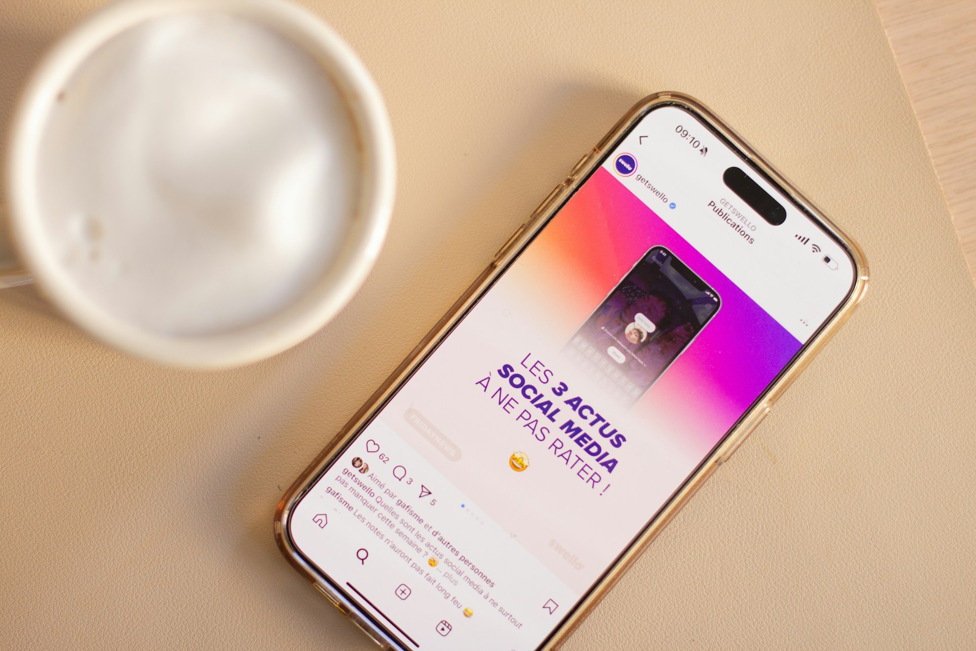 Phone displays social media news next to a coffee.
