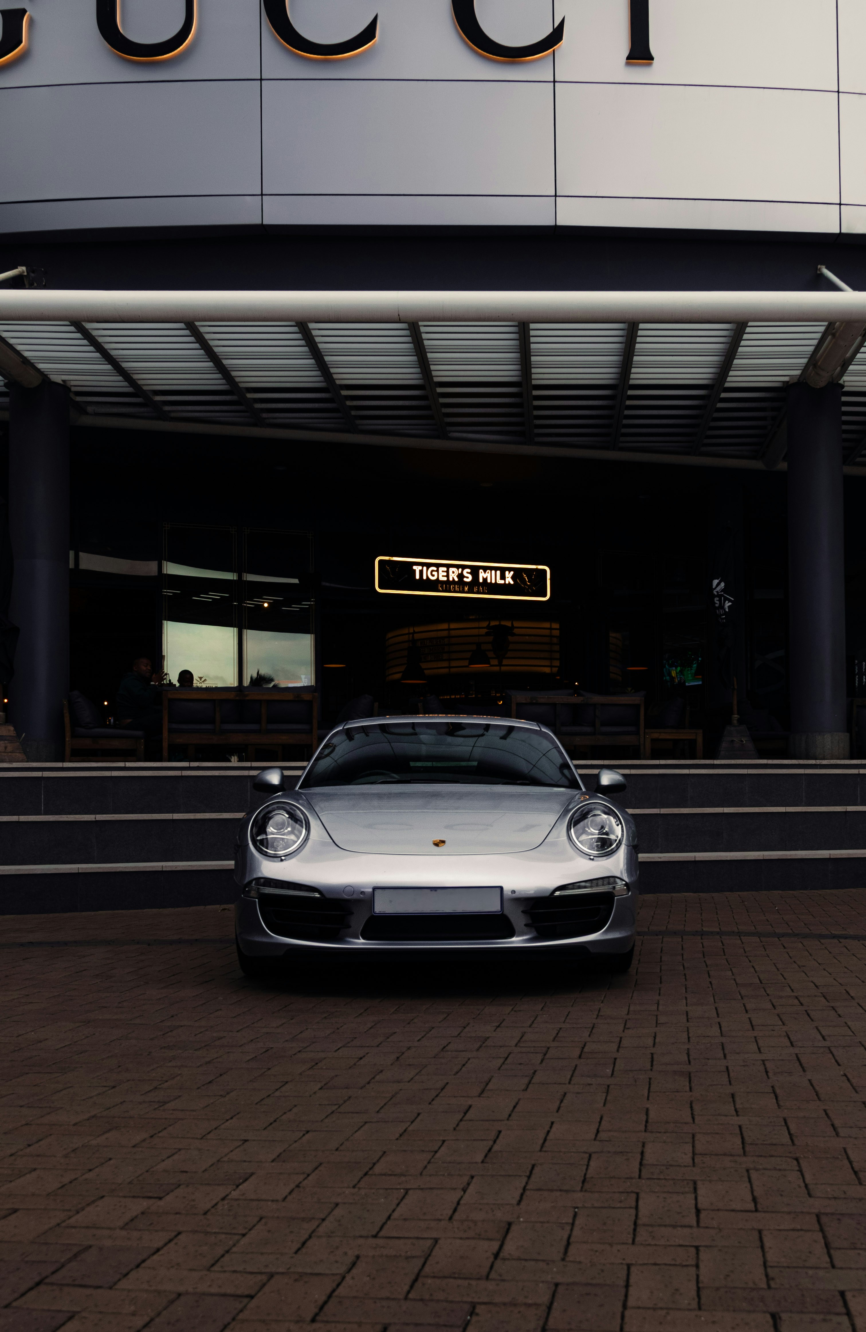 Silver porsche parked in front of gucci.