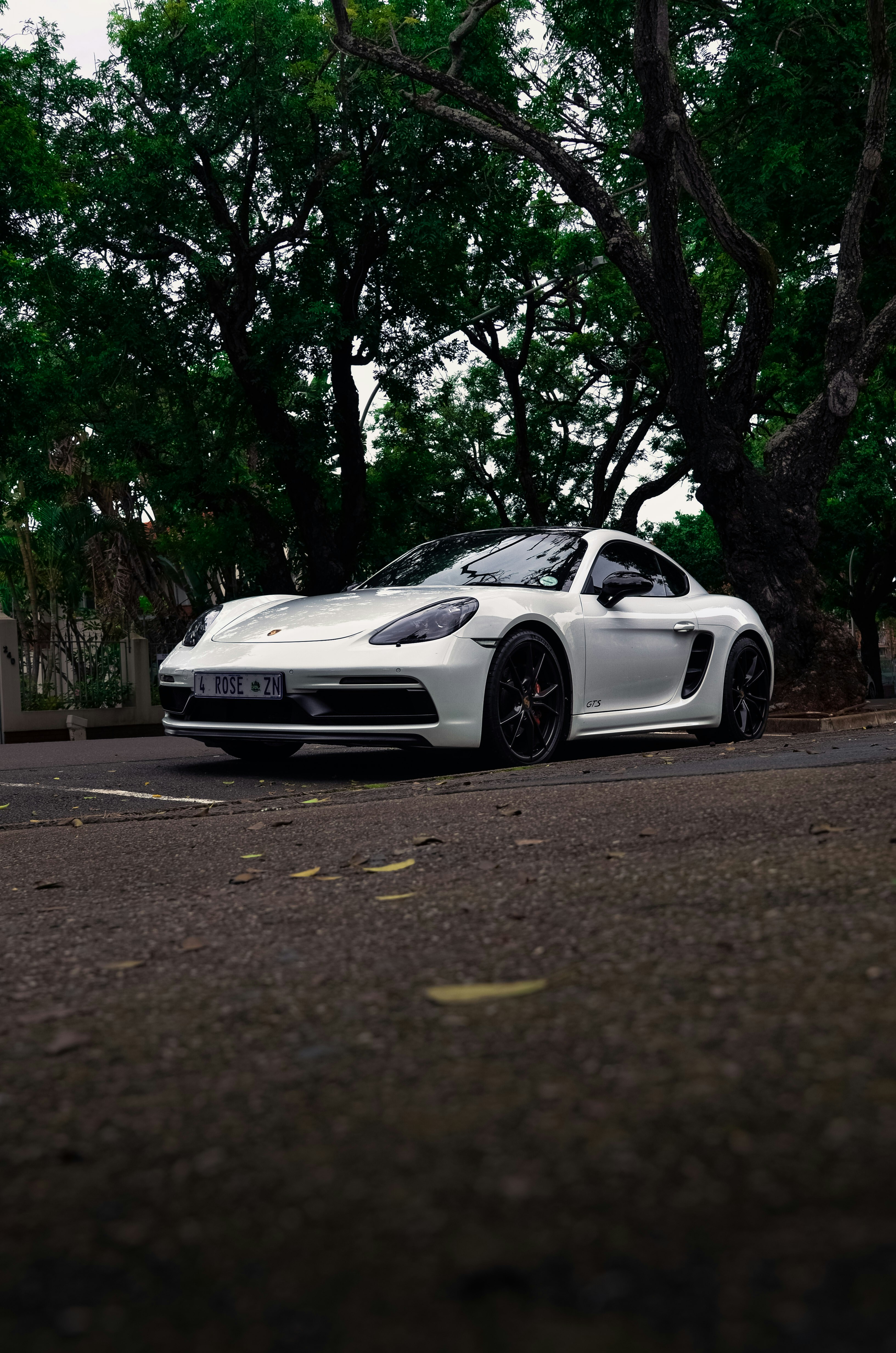 A white porsche is parked on a road.
