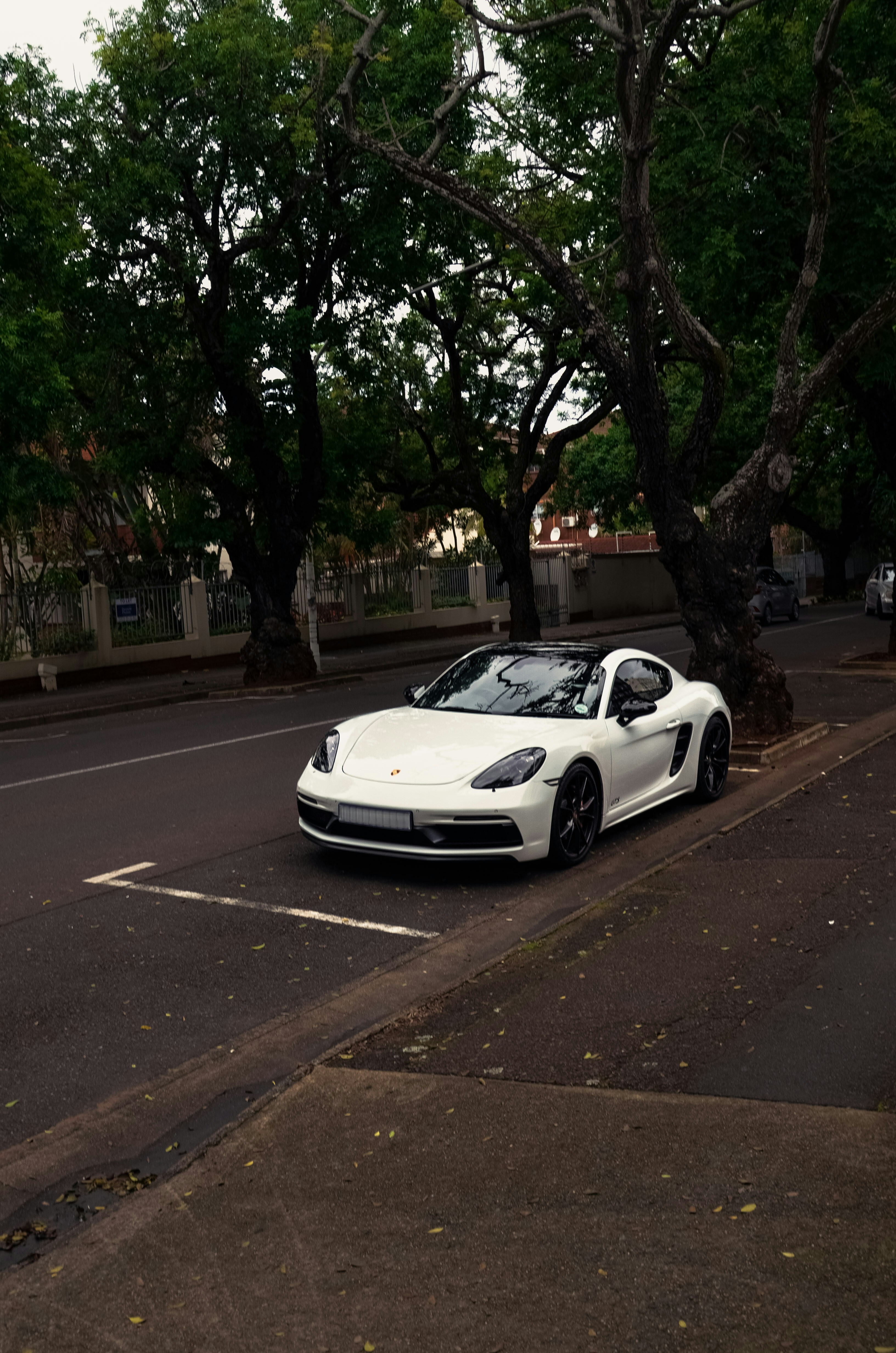 A white porsche is parked on the road.