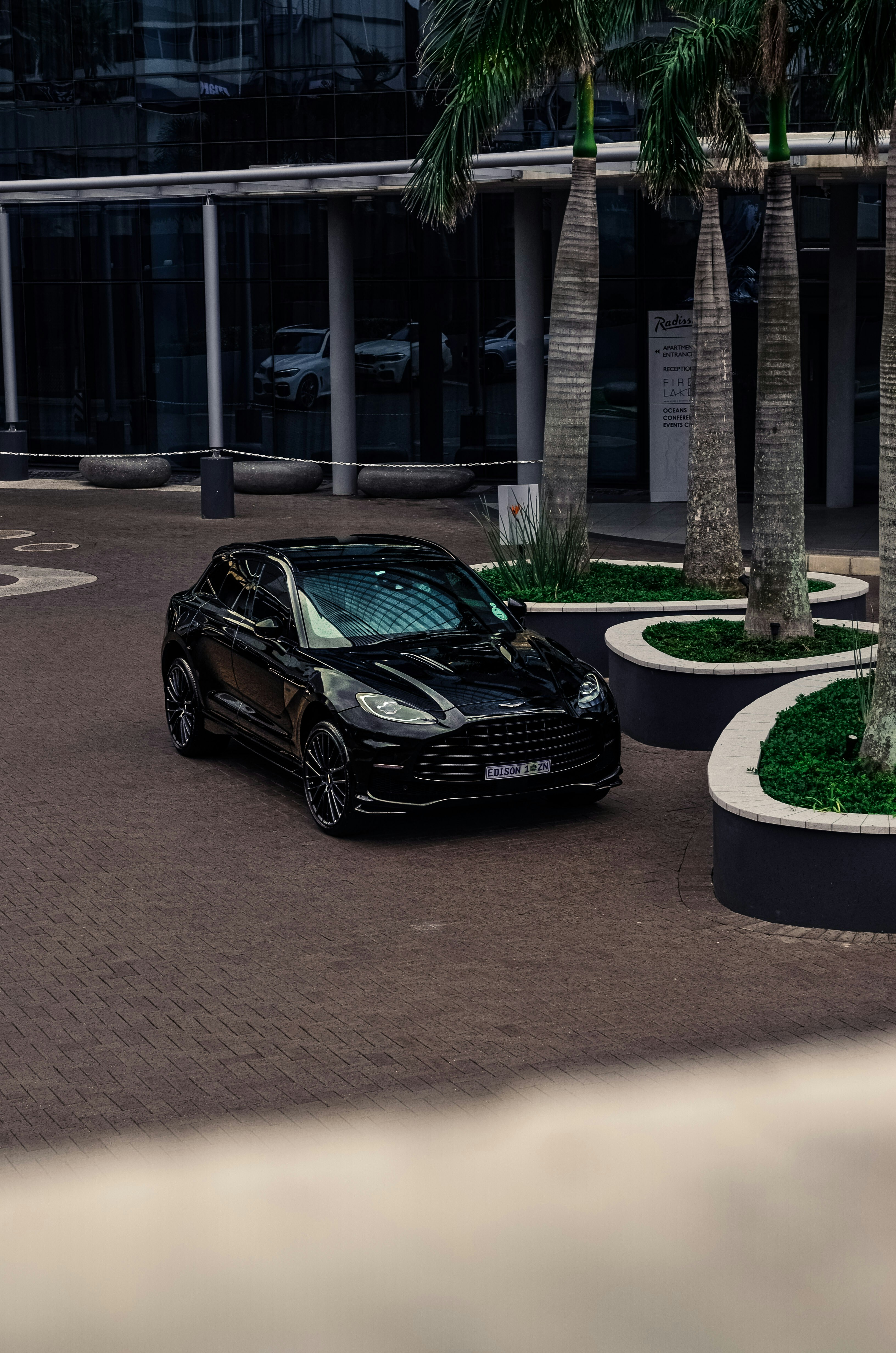 A black aston martin parked near a modern building.