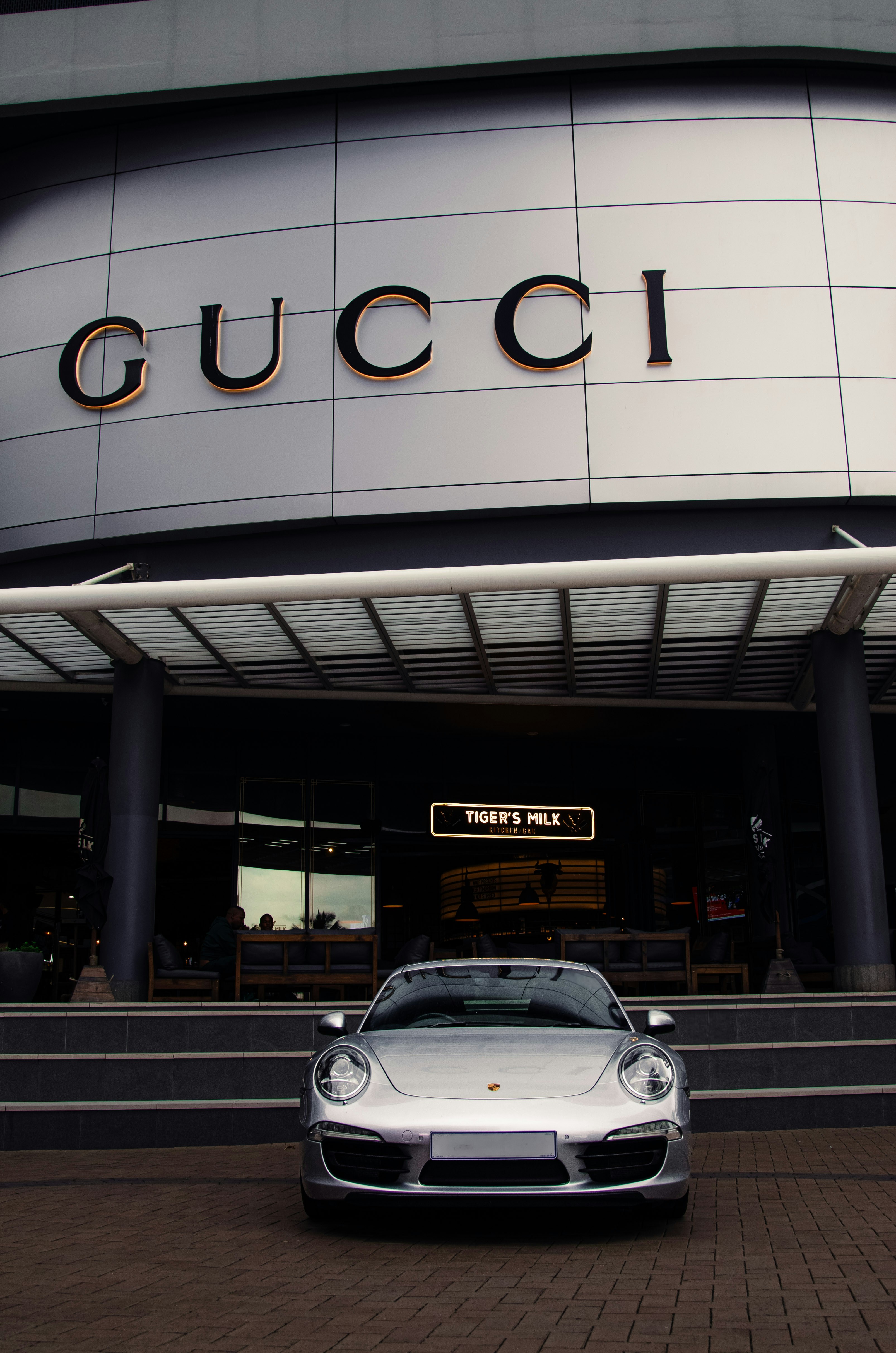 A luxury car is parked in front of gucci.