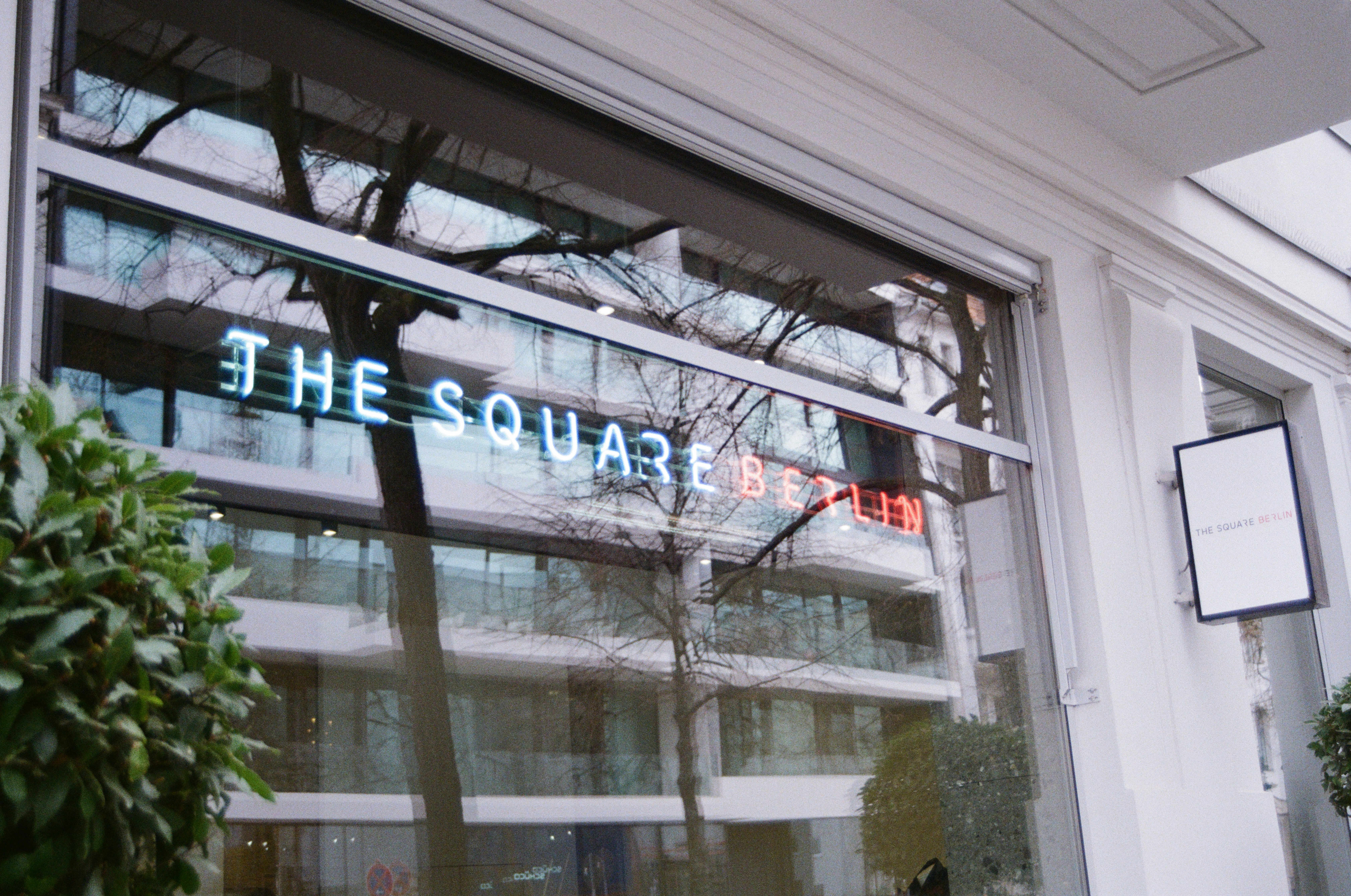 The square berlin neon sign reflects in window.