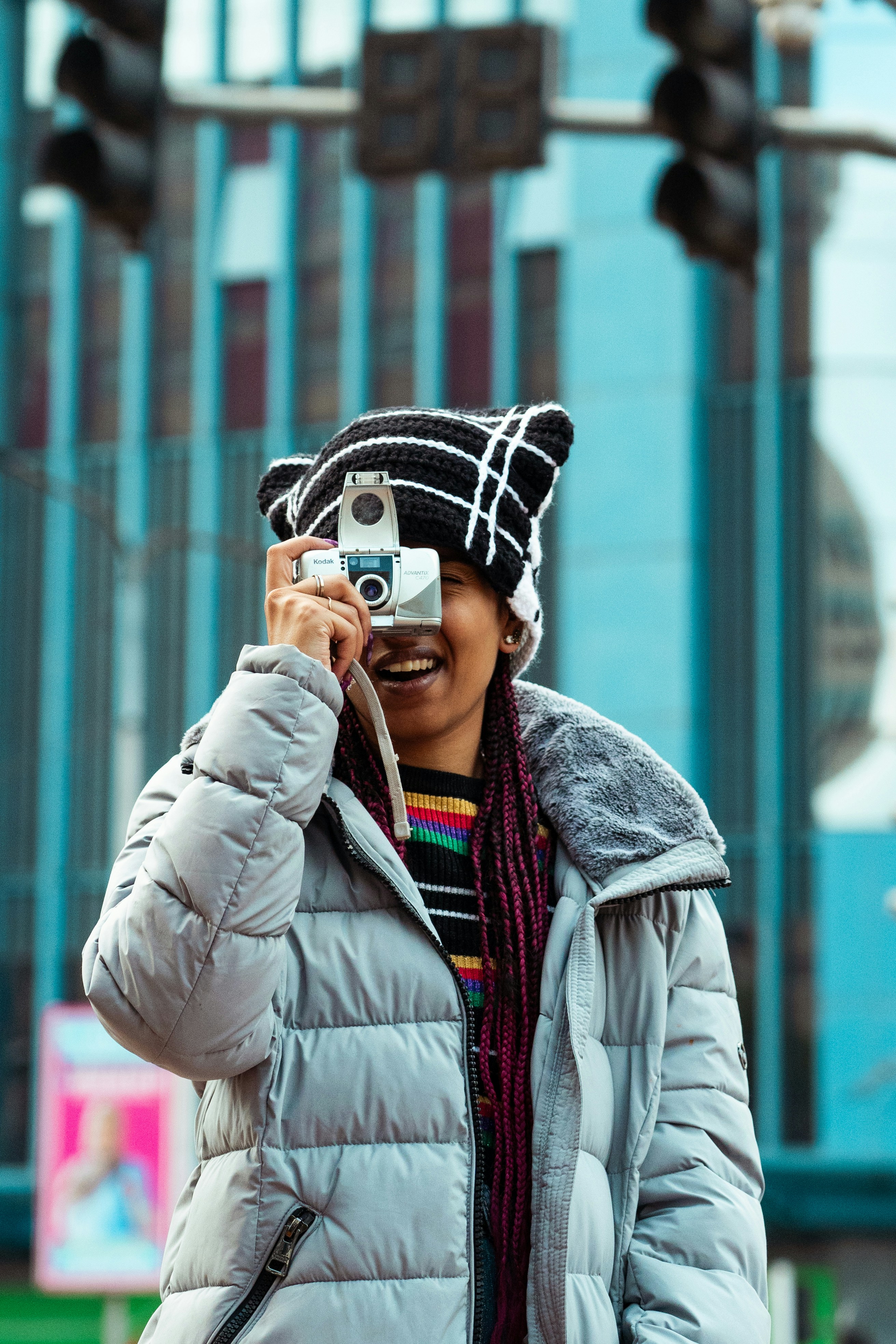Woman smiles as she photographs with a vintage camera.