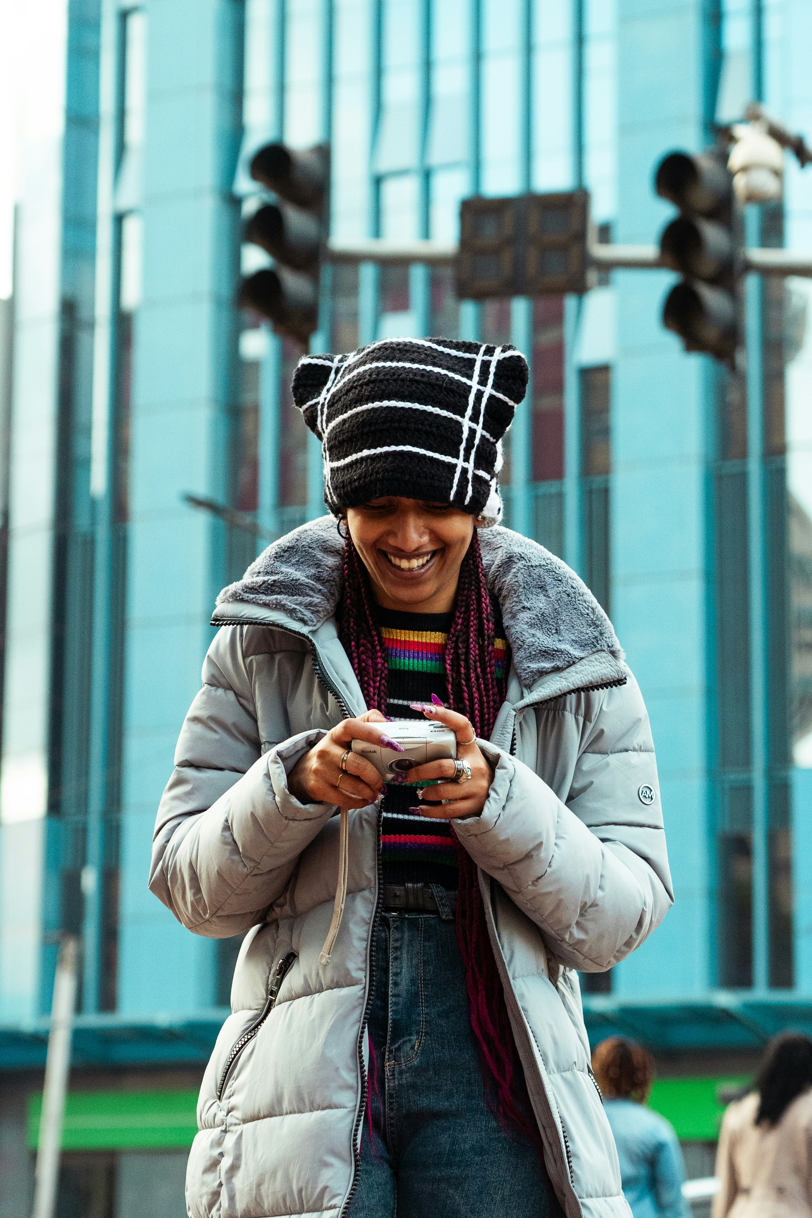 A woman smiles while looking at her camera.