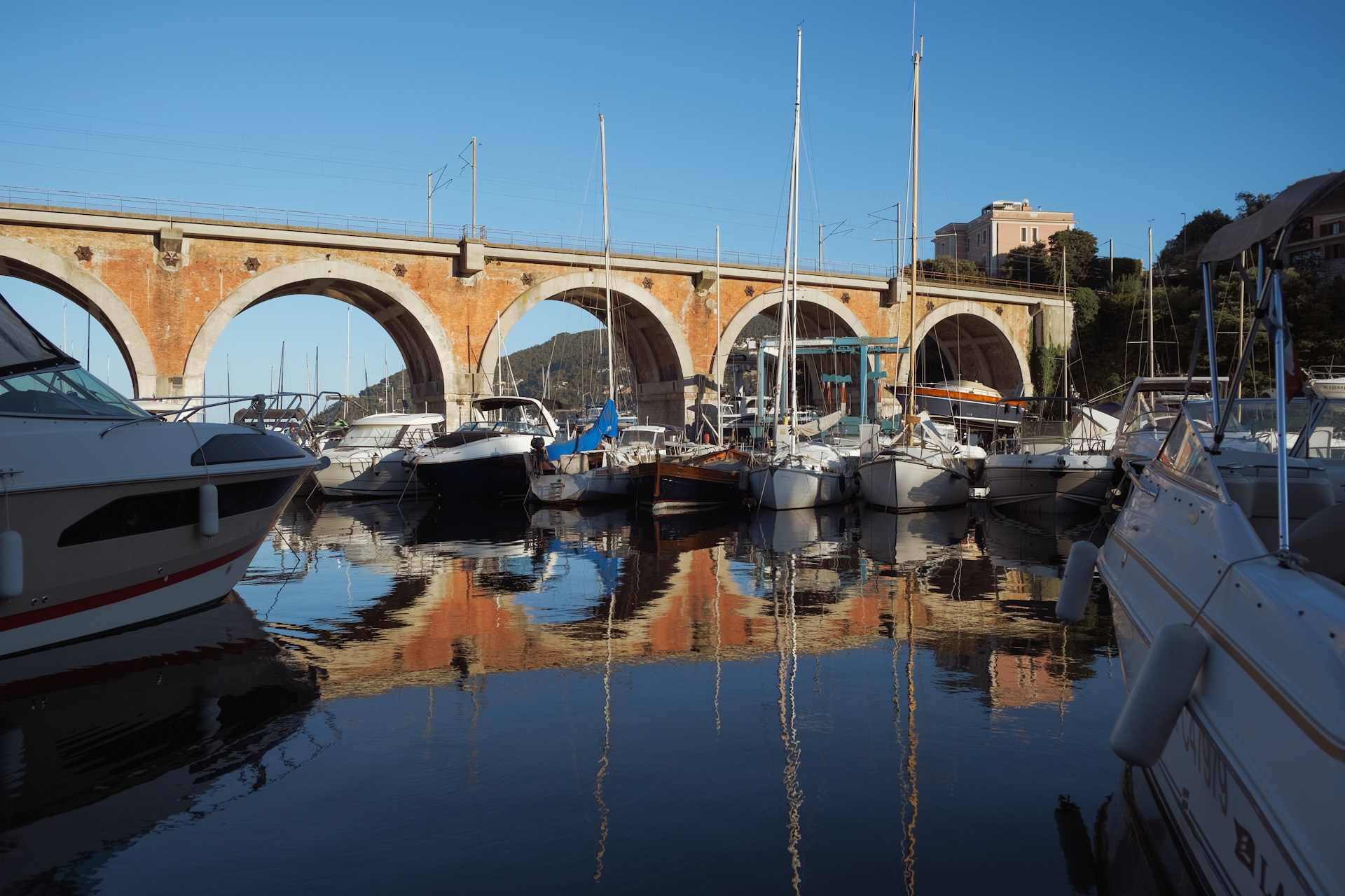 Boats are docked under a bridge in the harbor.
