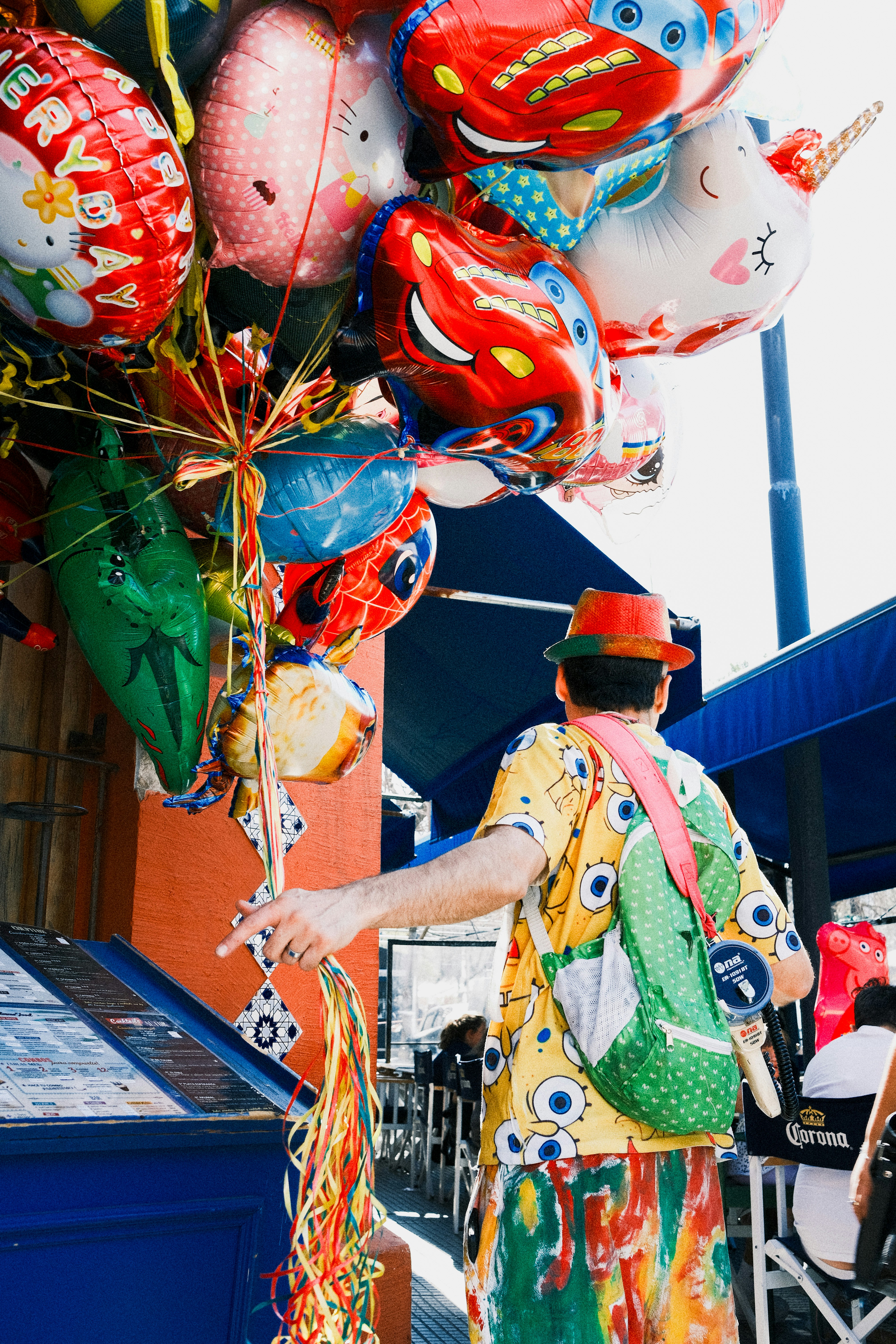 A clown holds a bunch of colorful character balloons.