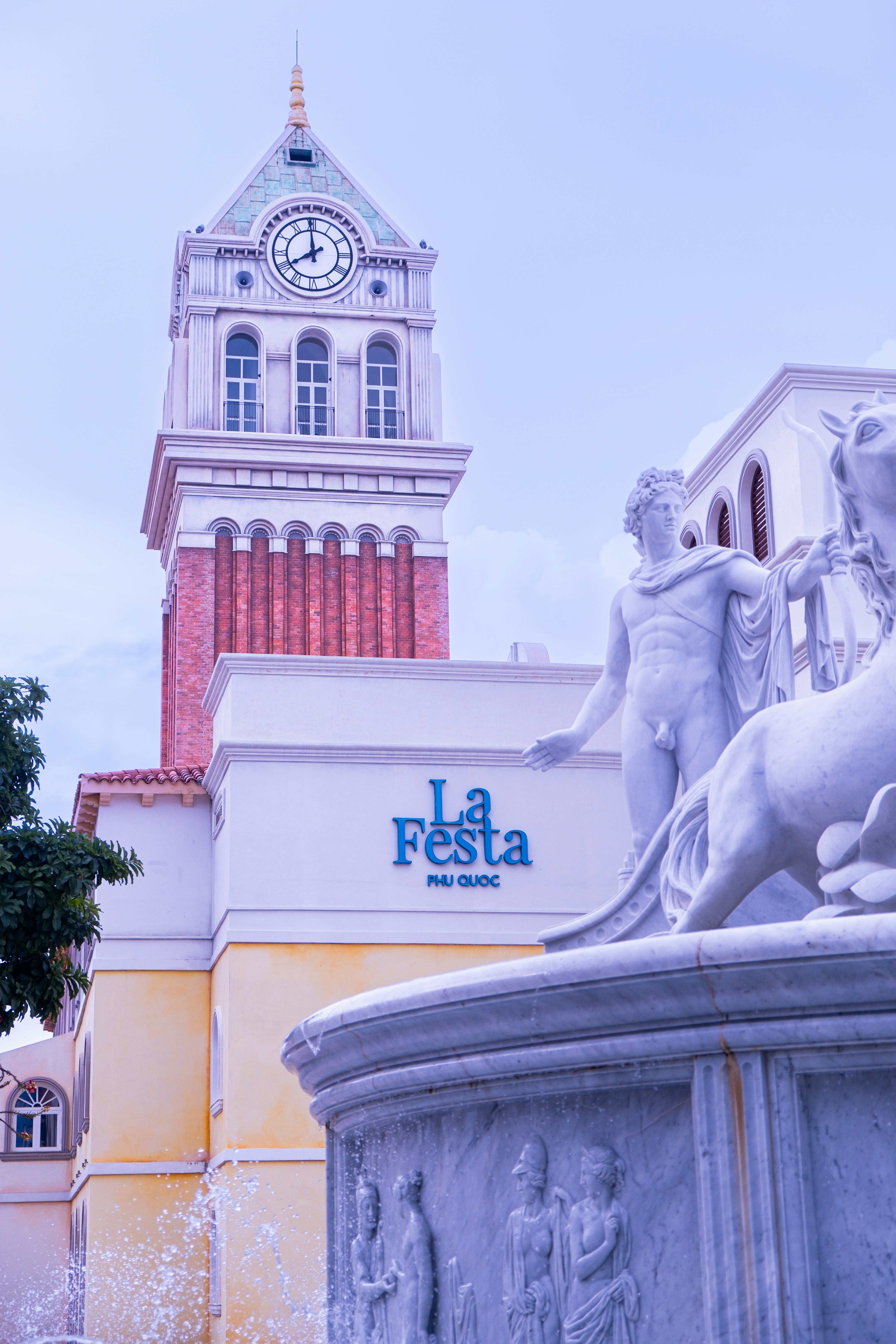 A clock tower and statue adorn a building's facade. photo – Free ...