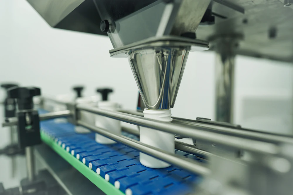 Automated filling head dosing oil into containers on the packing line