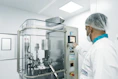 A worker operates machinery in a cleanroom.