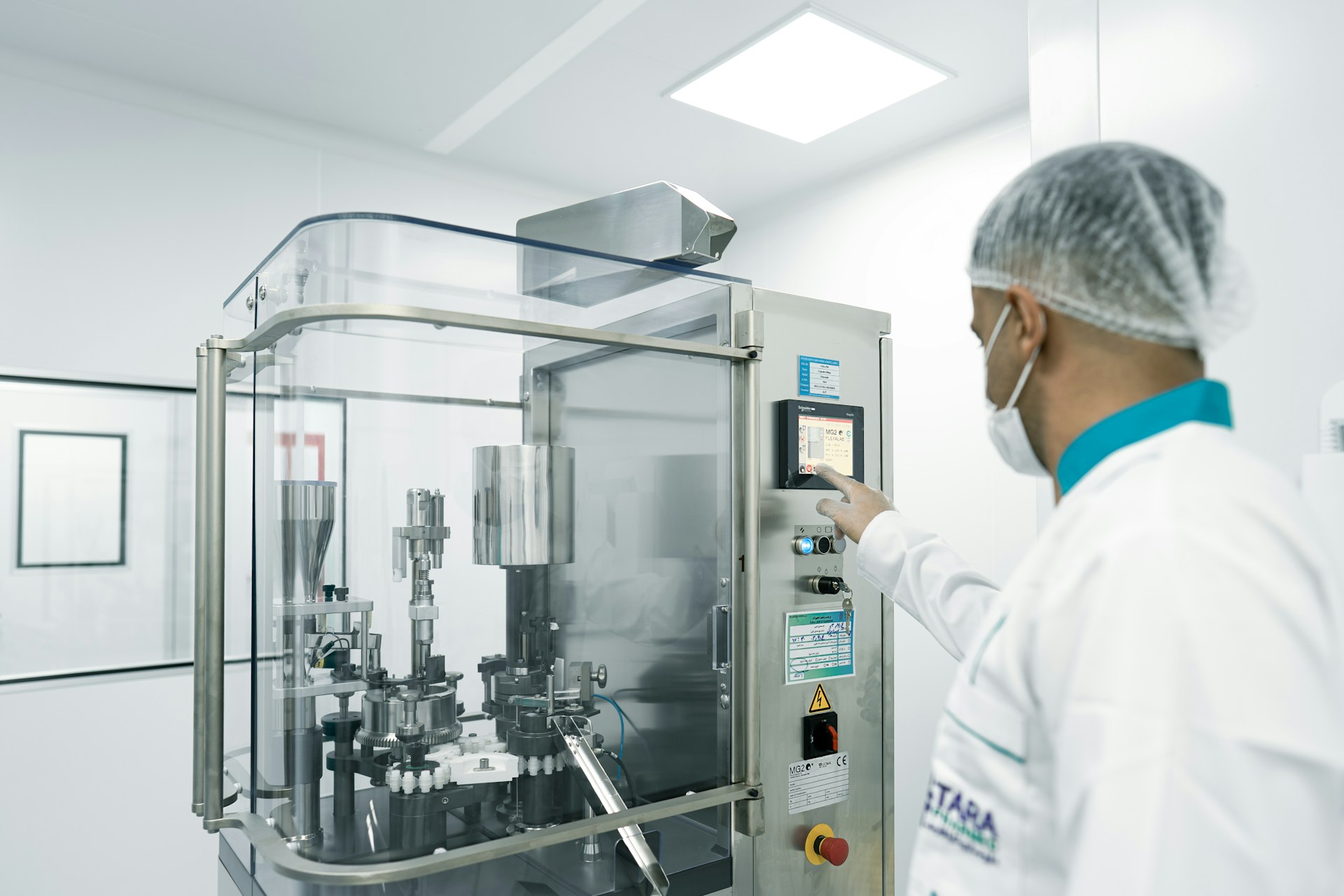 A worker operates machinery in a cleanroom.