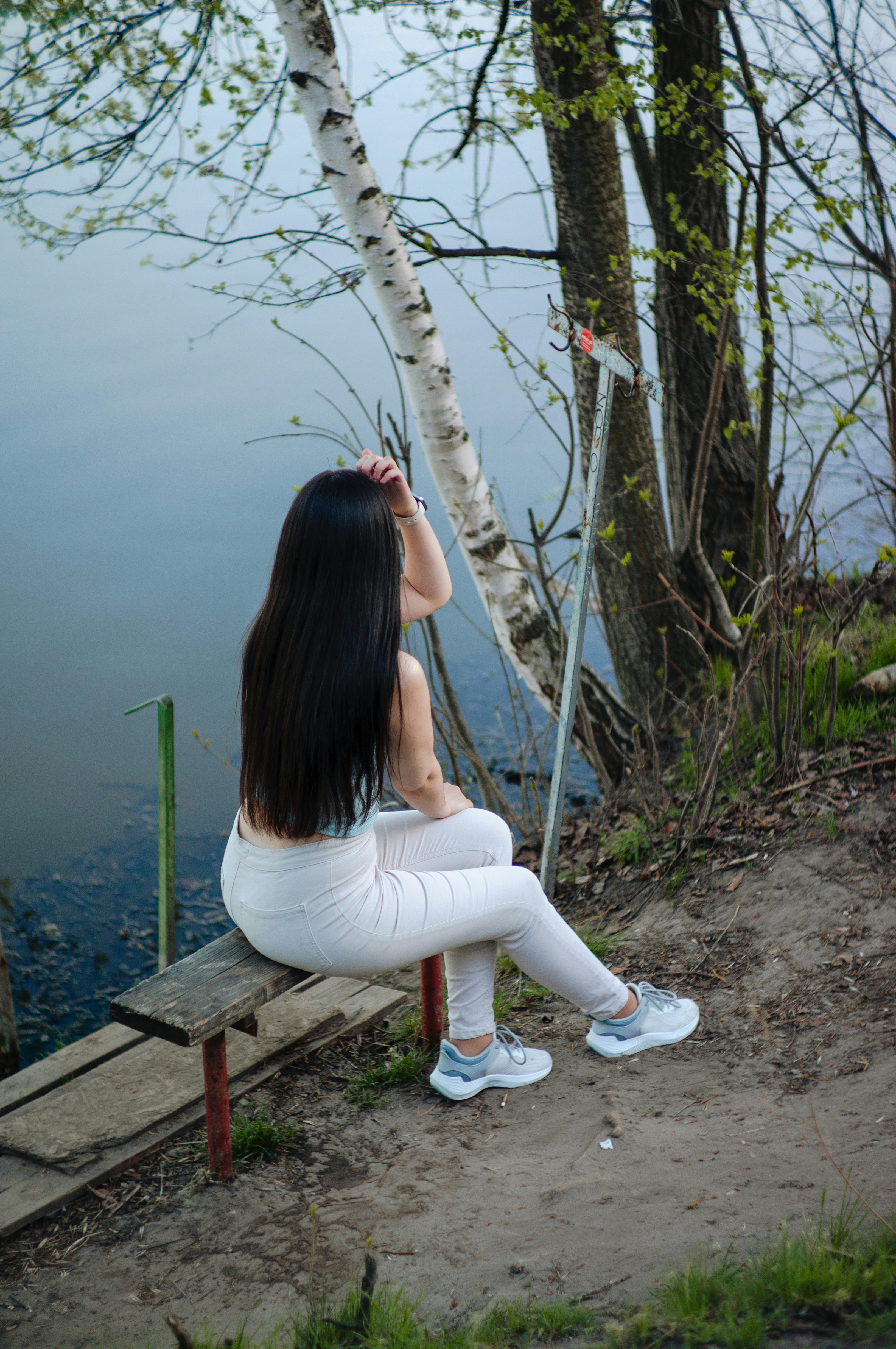 Frau sitzt auf einer Bank und schaut auf das Wasser.
