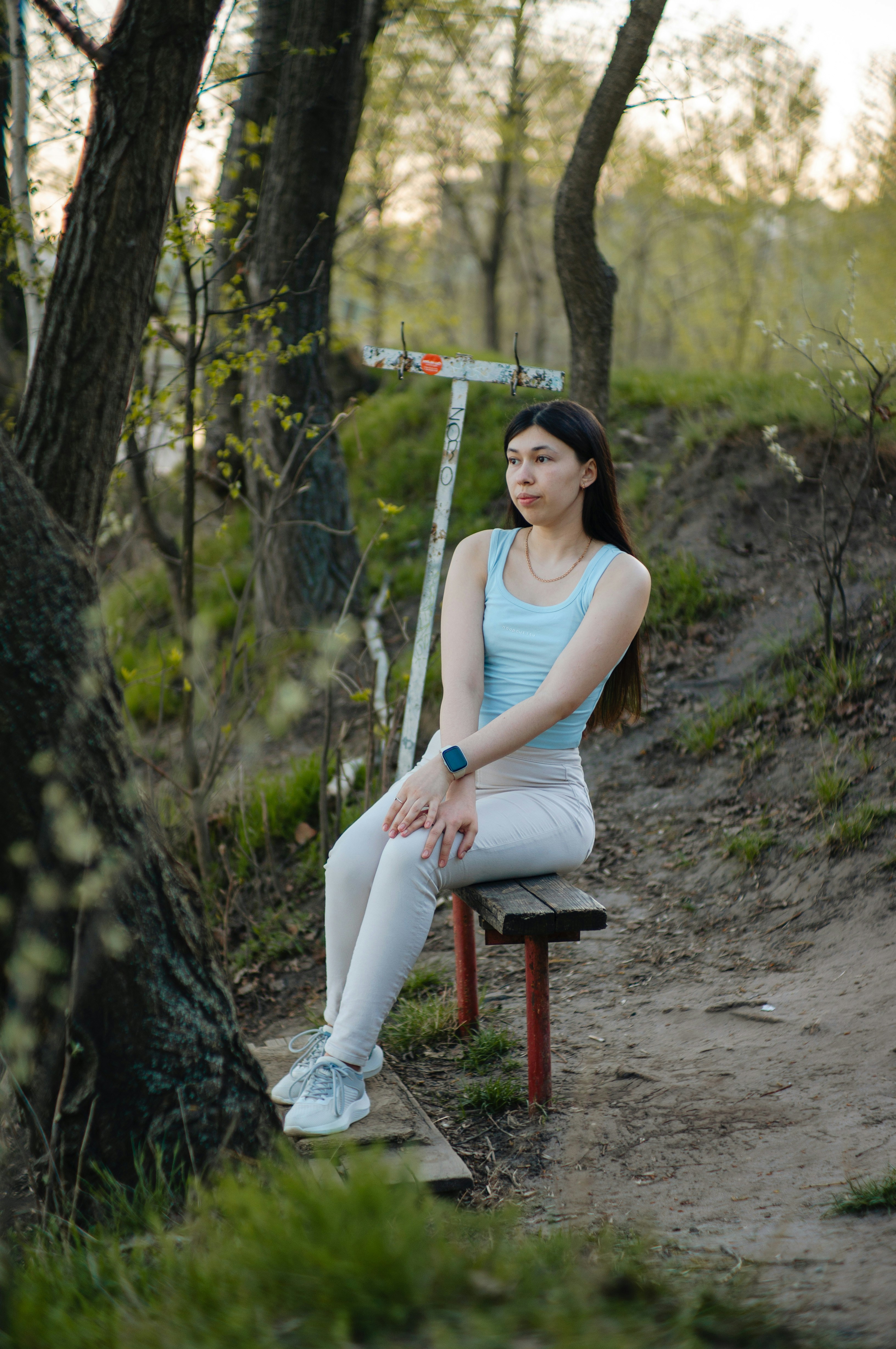 Eine junge Frau sitzt auf einer Parkbank.