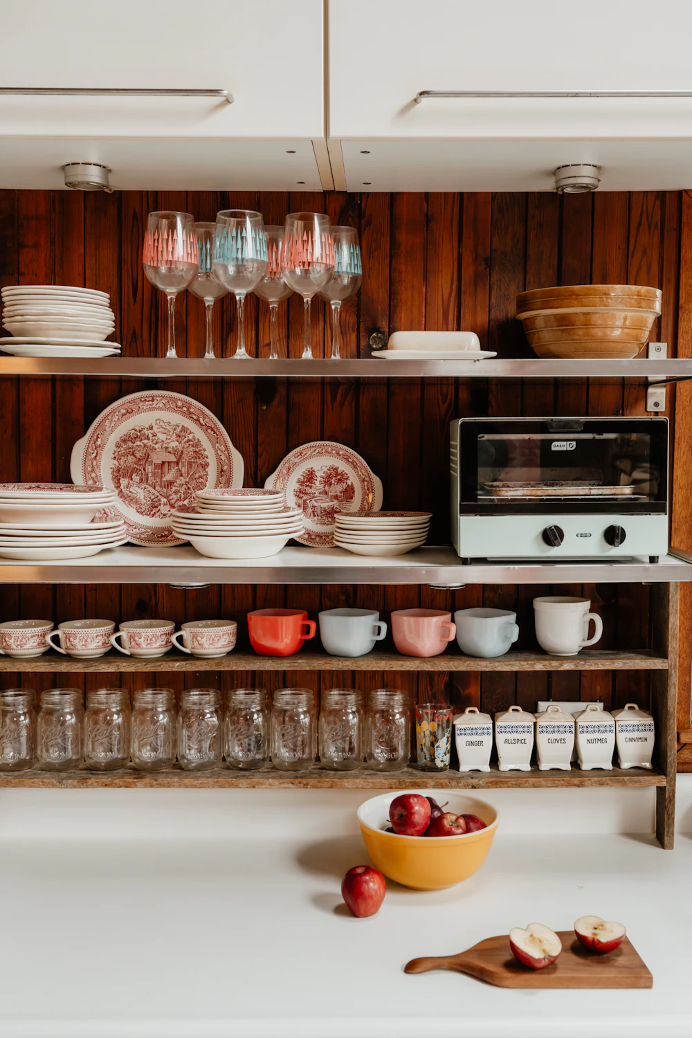 A kitchen shelf with jars and glassware