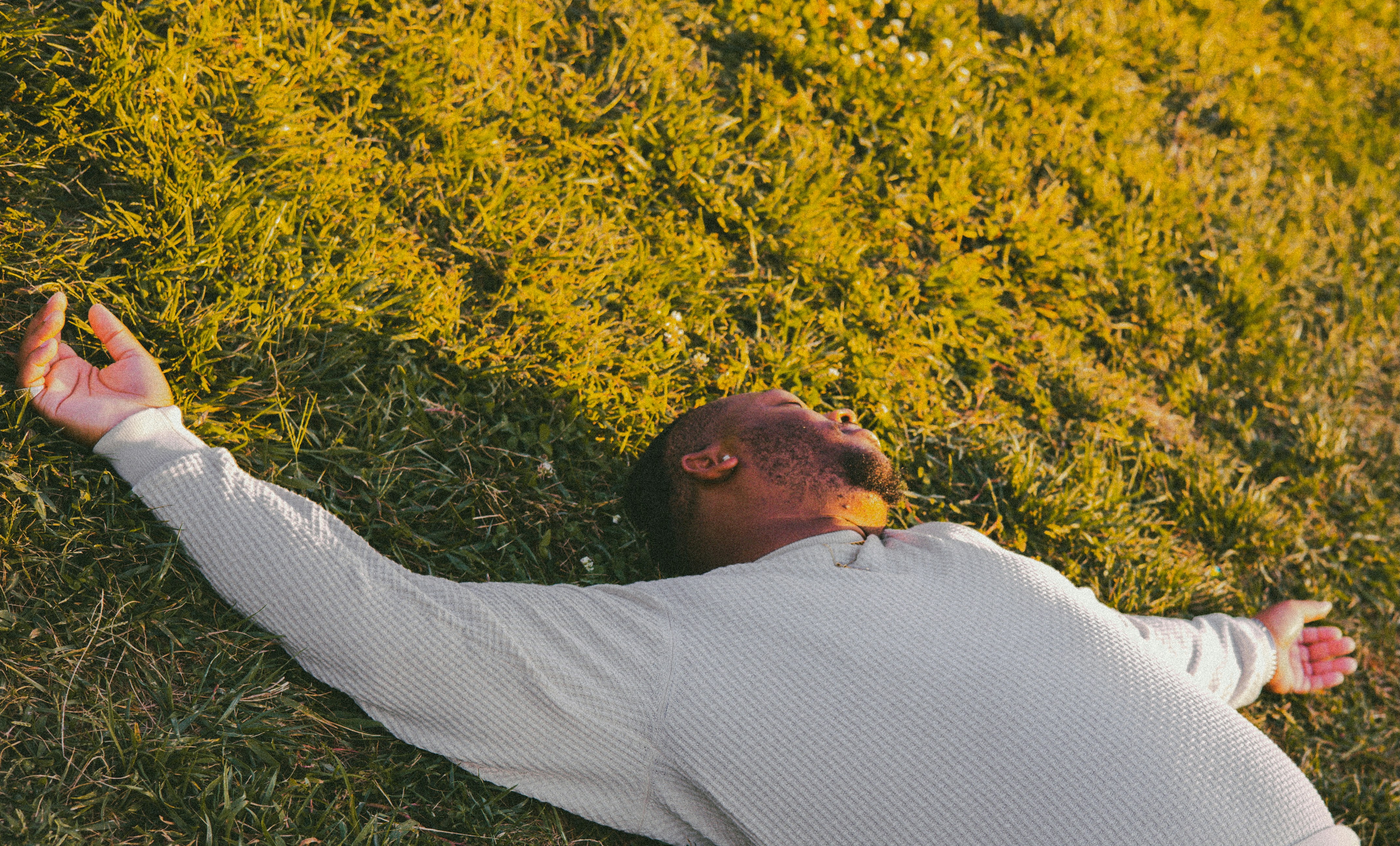 A person lying on grass with arms outstretched.