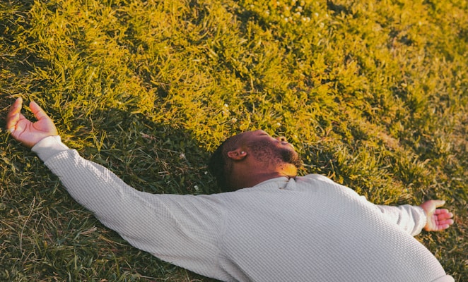 Person lying on grass with arms outstretched relaxing