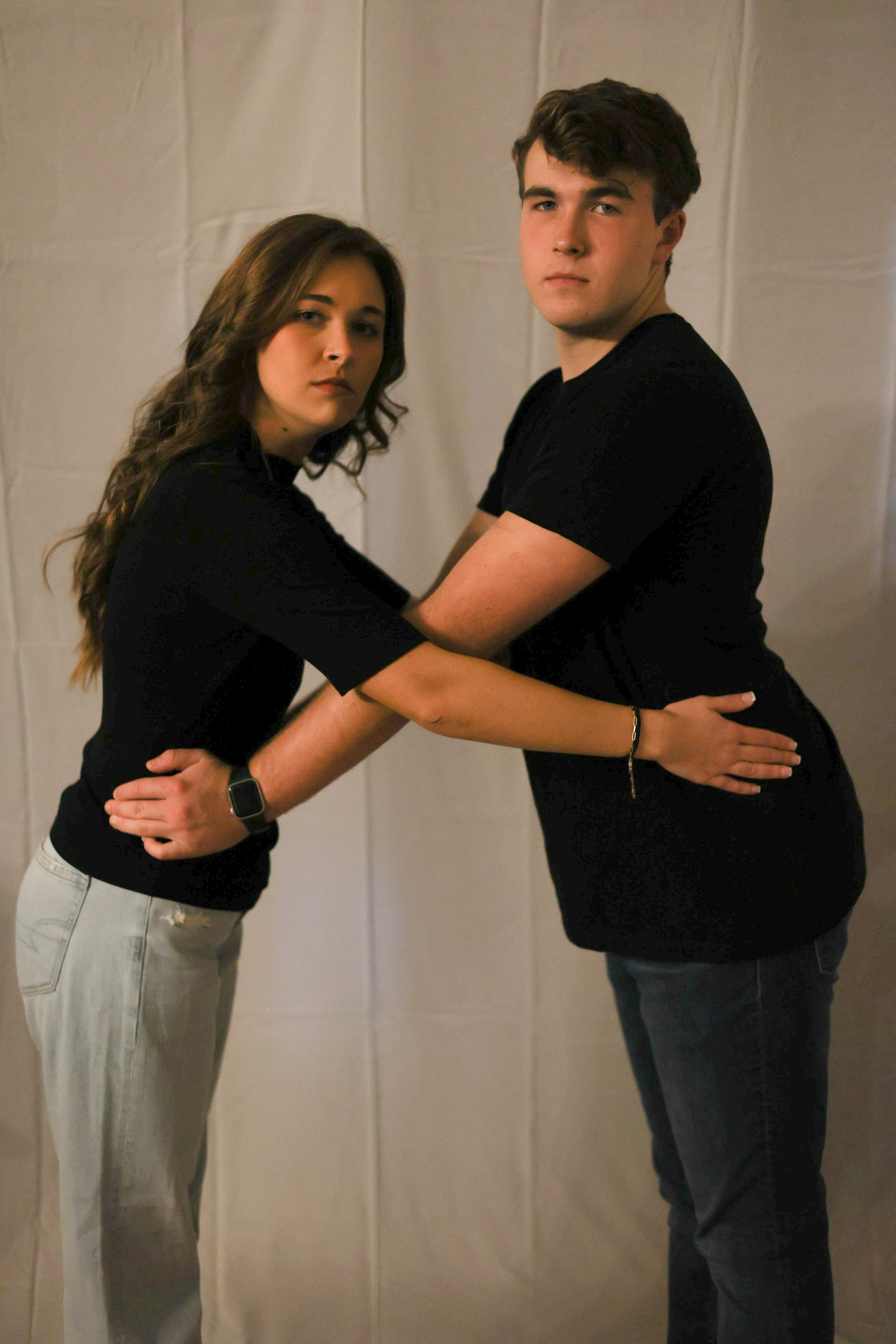 Two people pose for a photo with their arms crossed.
