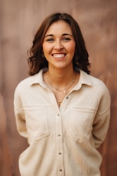 A smiling woman poses in front of a wall.