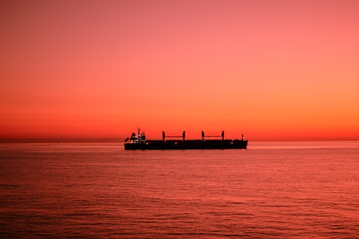 A ship sails on the ocean at sunset.