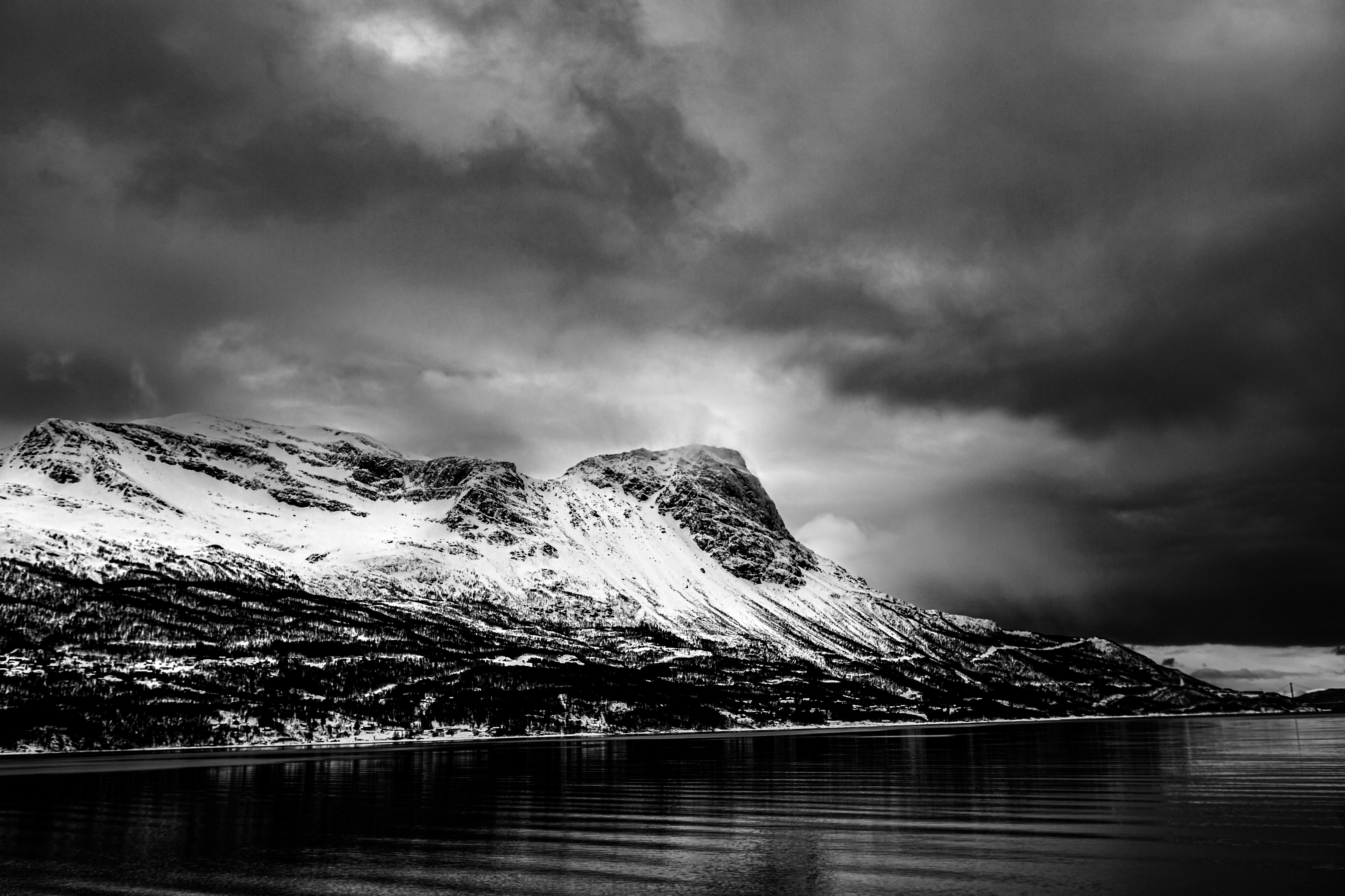 Snowy mountains loom under a cloudy, ominous sky.
