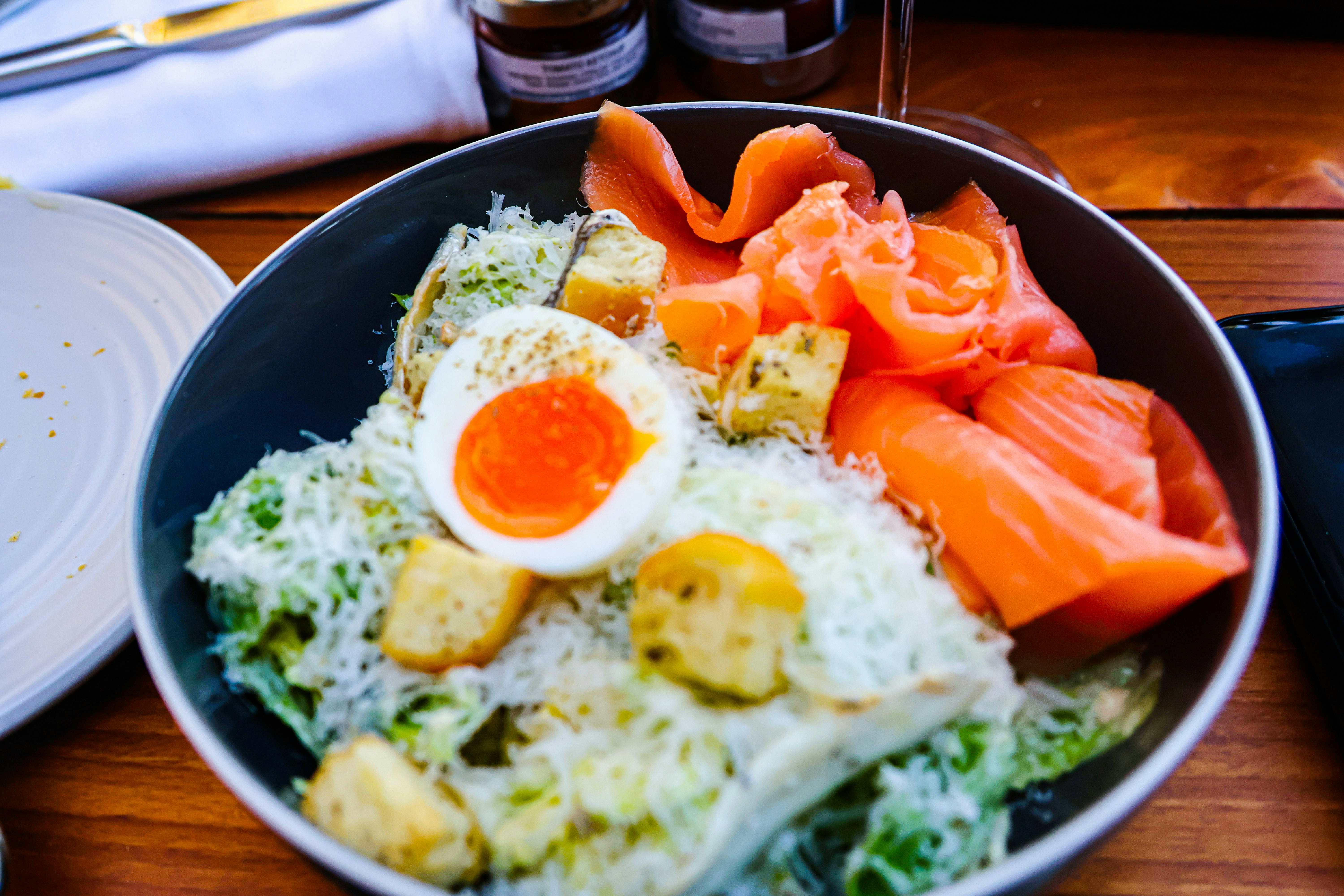 A bowl of salad with egg and salmon.
