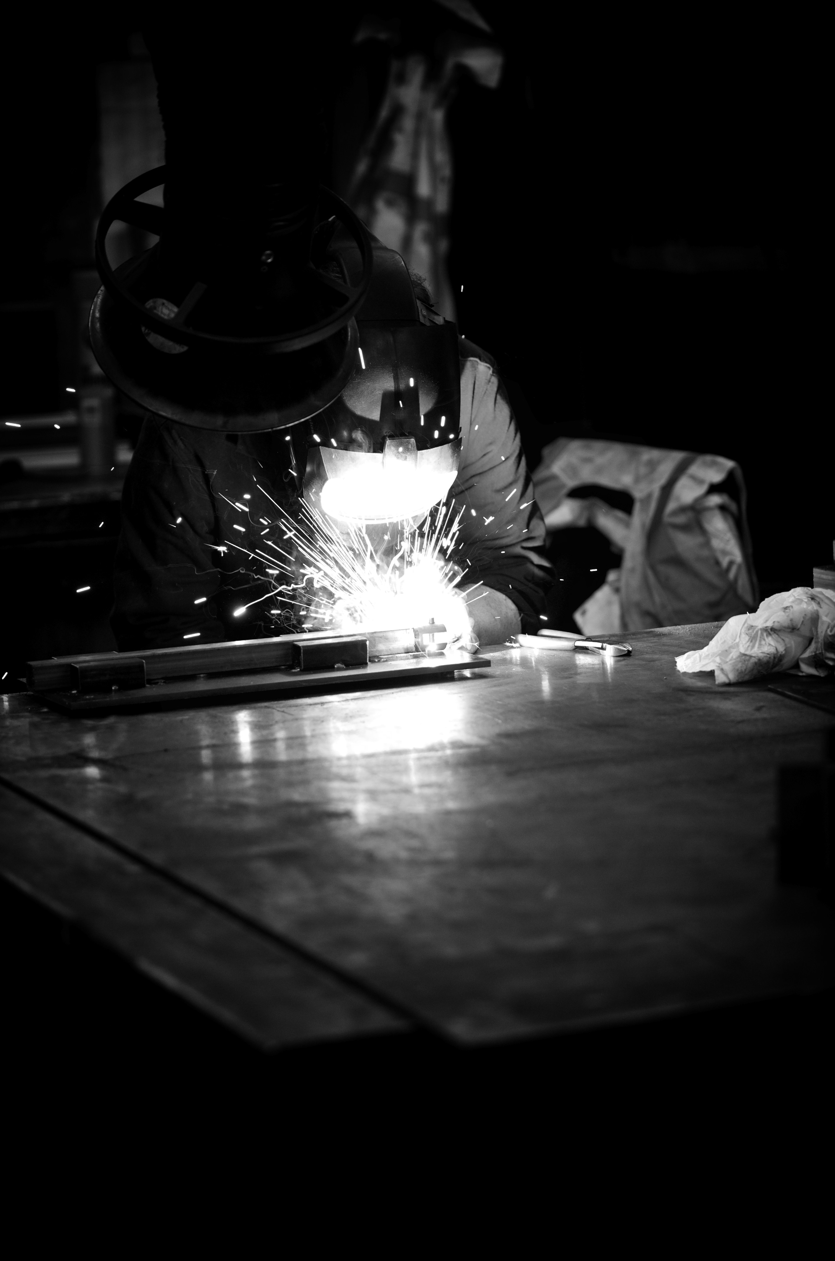 Welder is working, creating sparks in the dark.