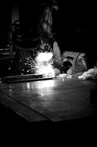 Welder is working, creating sparks in the dark.