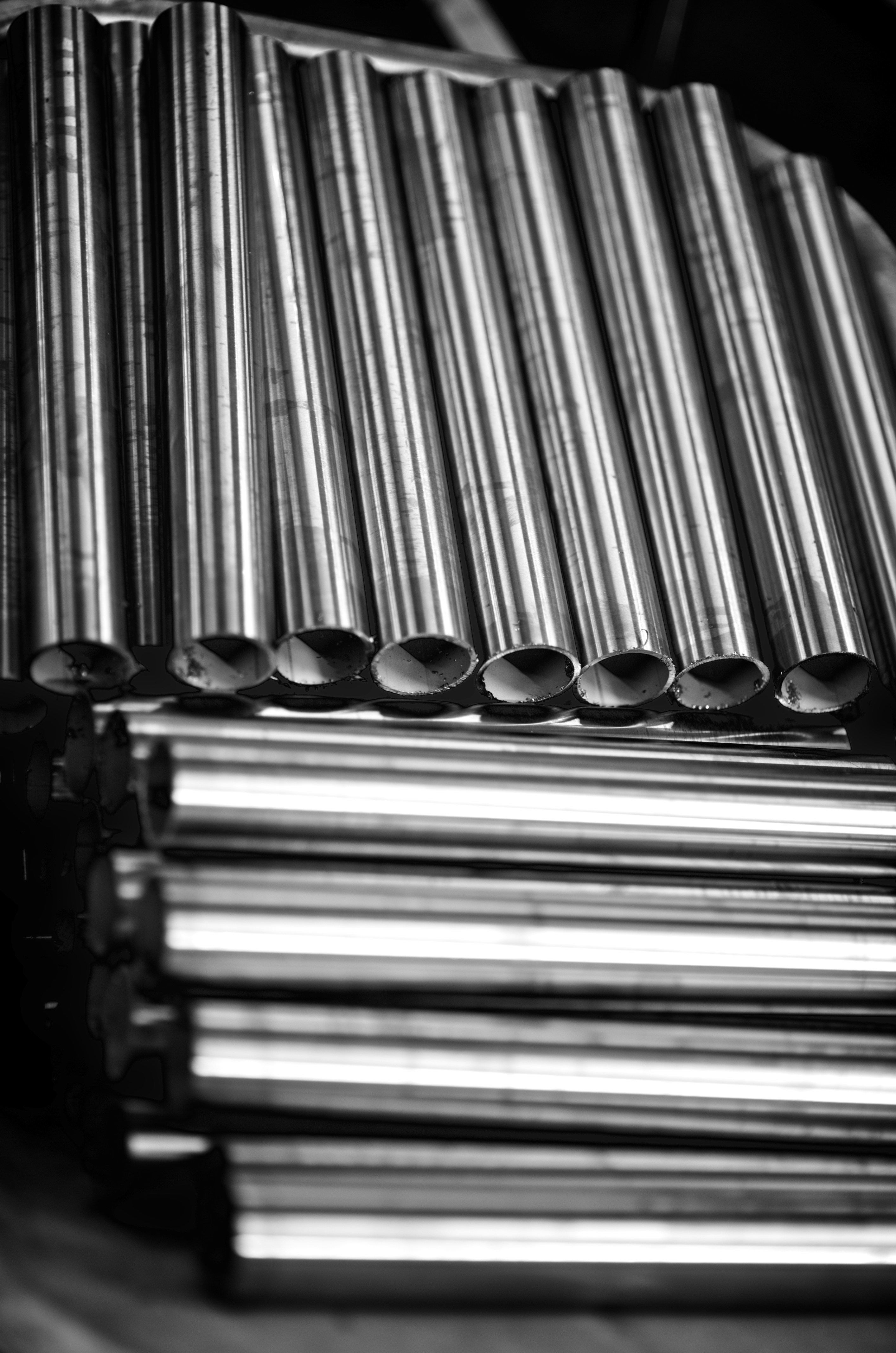 Metal tubes are stacked in a factory.