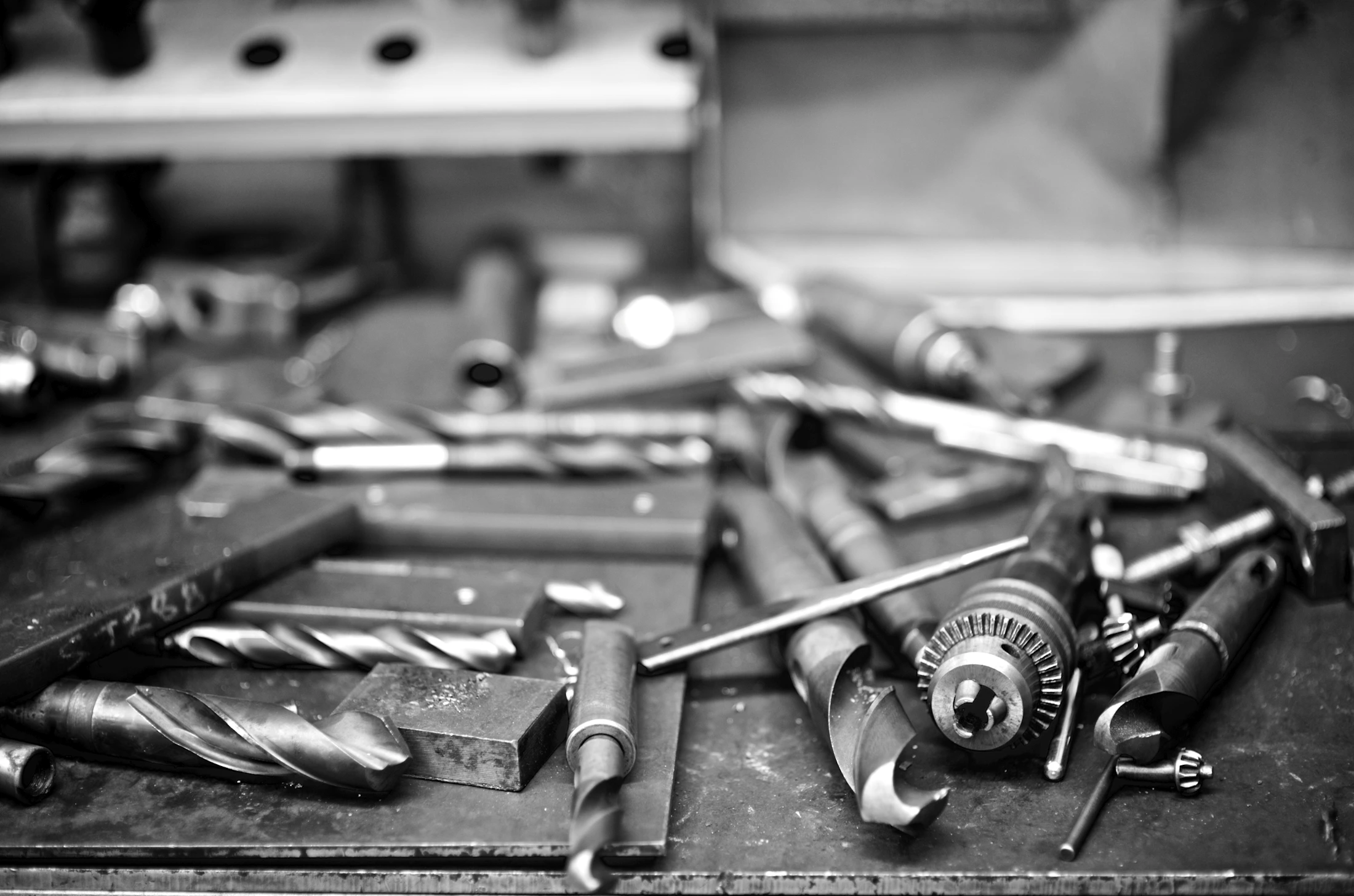Drill bits and metal workshop tools arranged across an active workbench