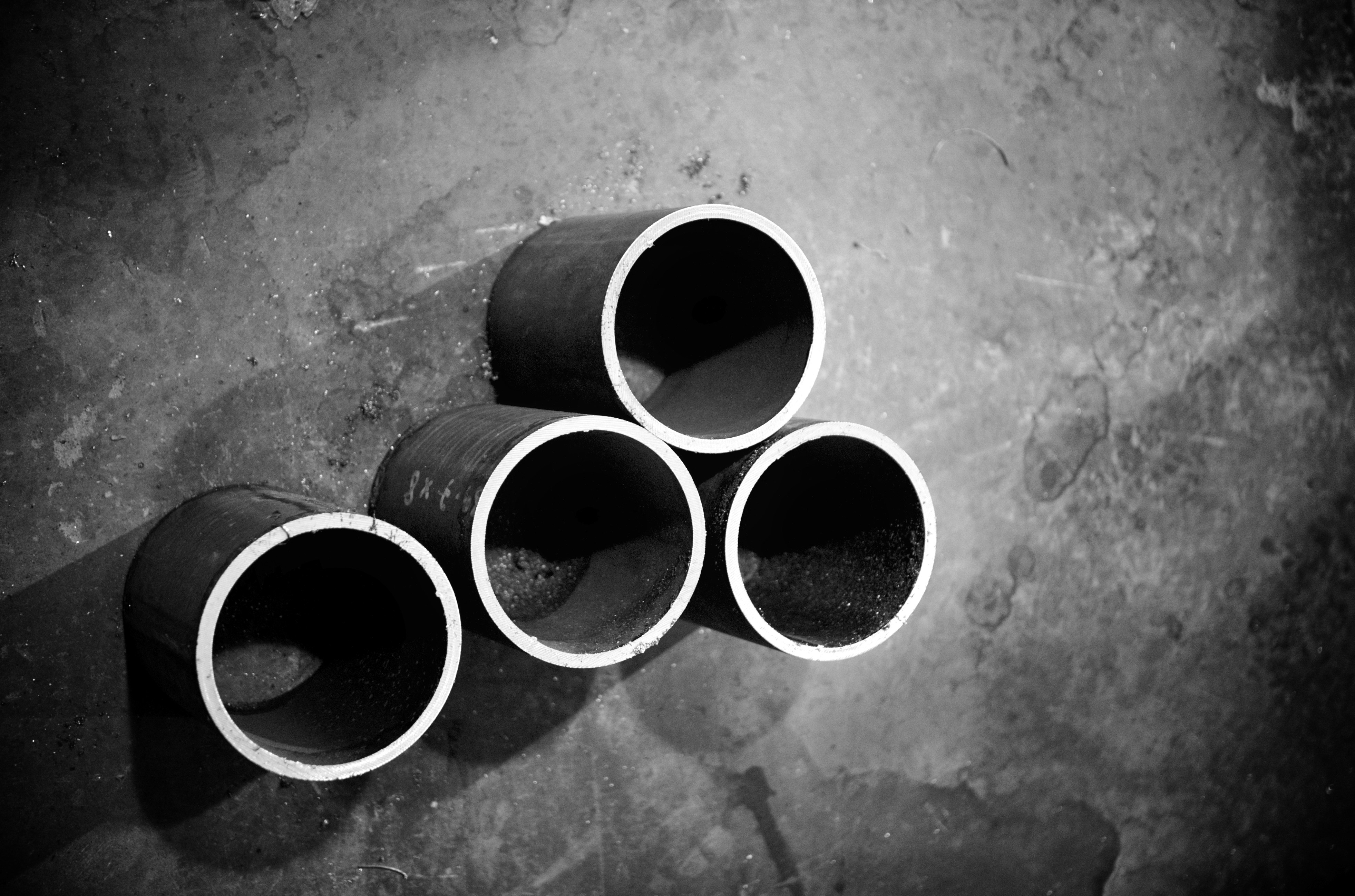 Four cylindrical pipes lay upon the ground.