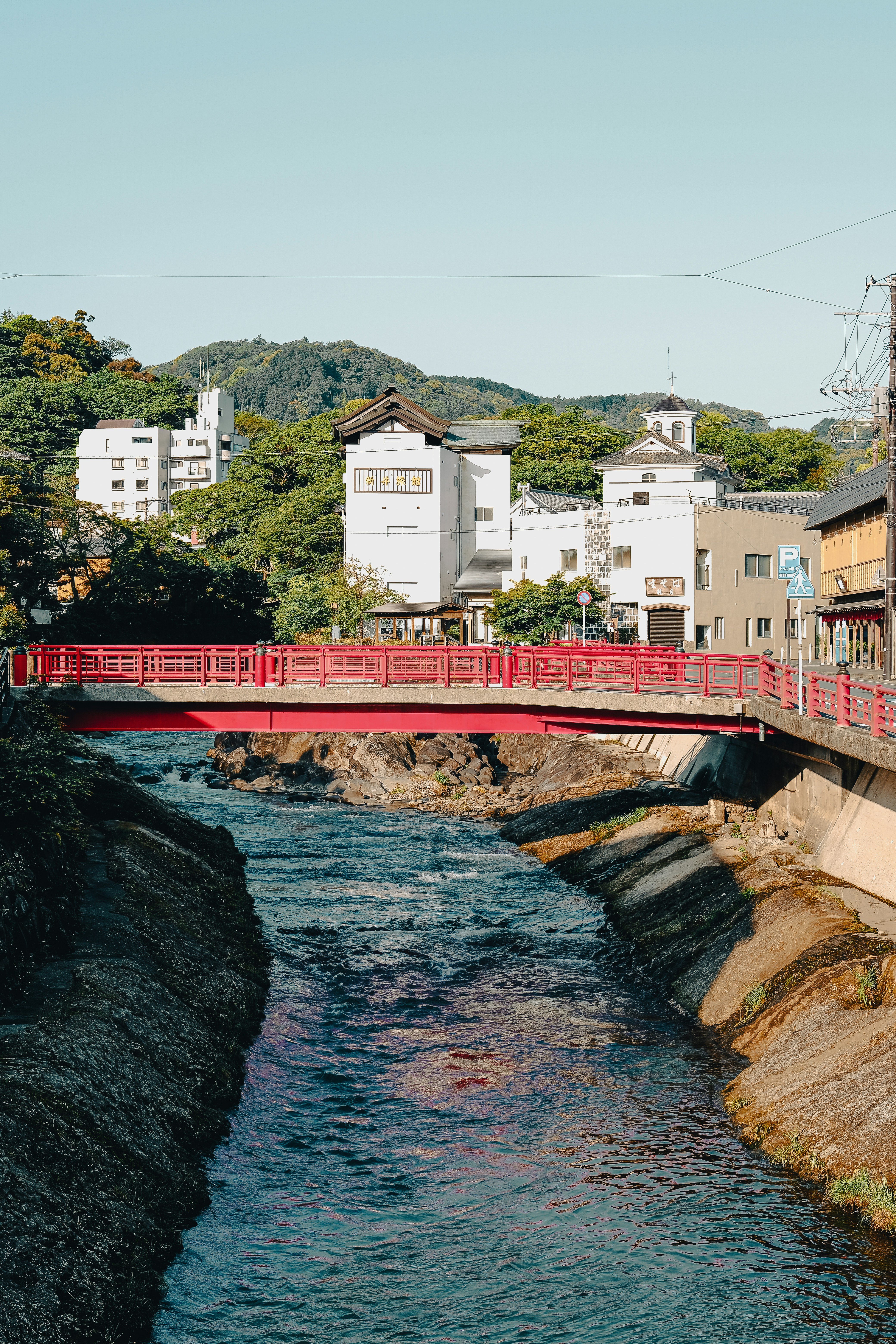 빨간 다리가 경치 좋은 마을의 강을 건너고 있습니다.