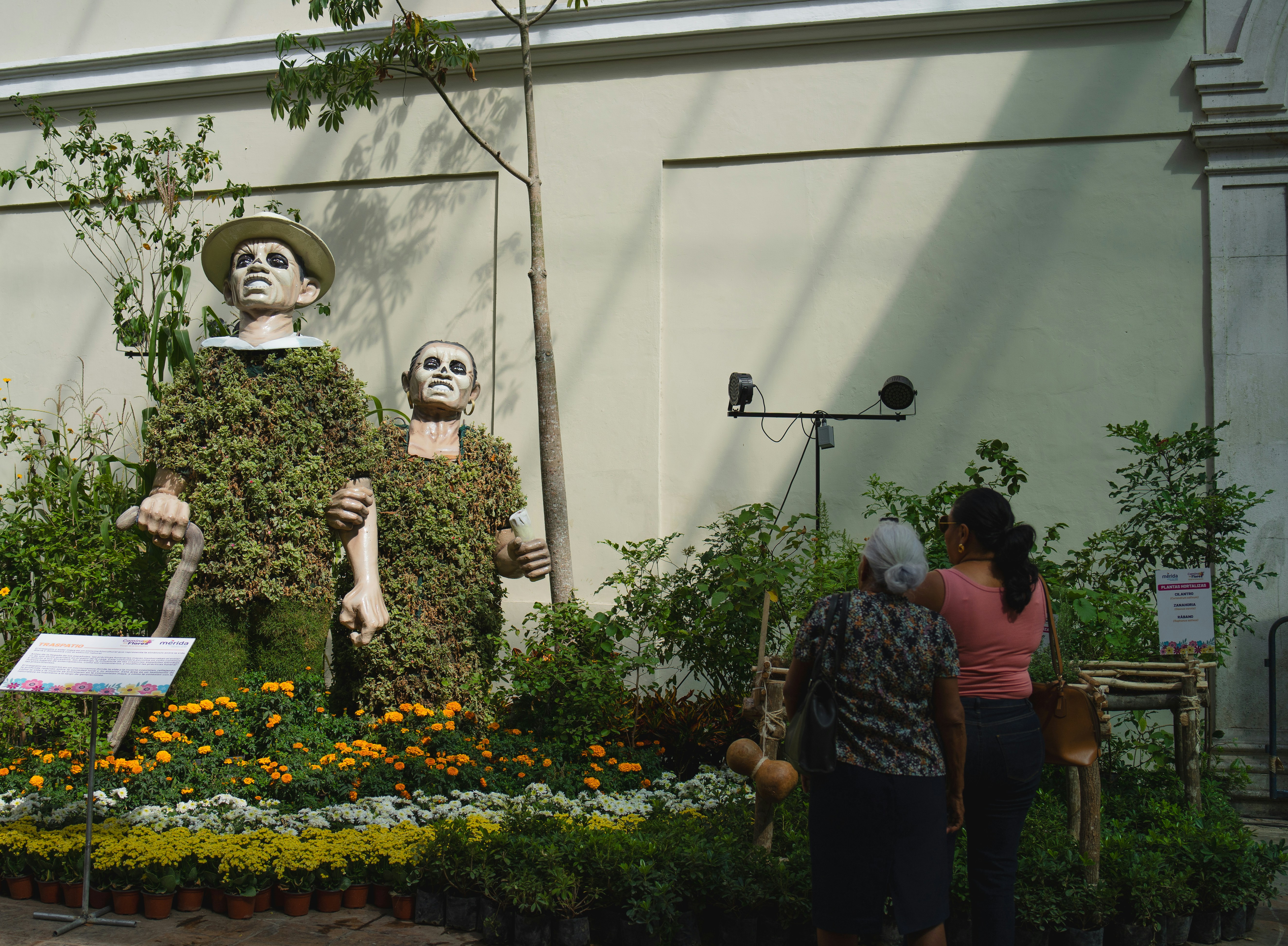 Two figures made of plants and two women viewing them.