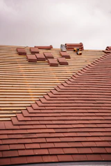Roof tiles are being installed on a wooden frame.