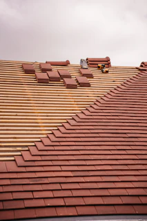Roof tiles are being installed on a wooden frame.