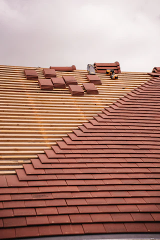 Roof tiles are being installed on a wooden frame.