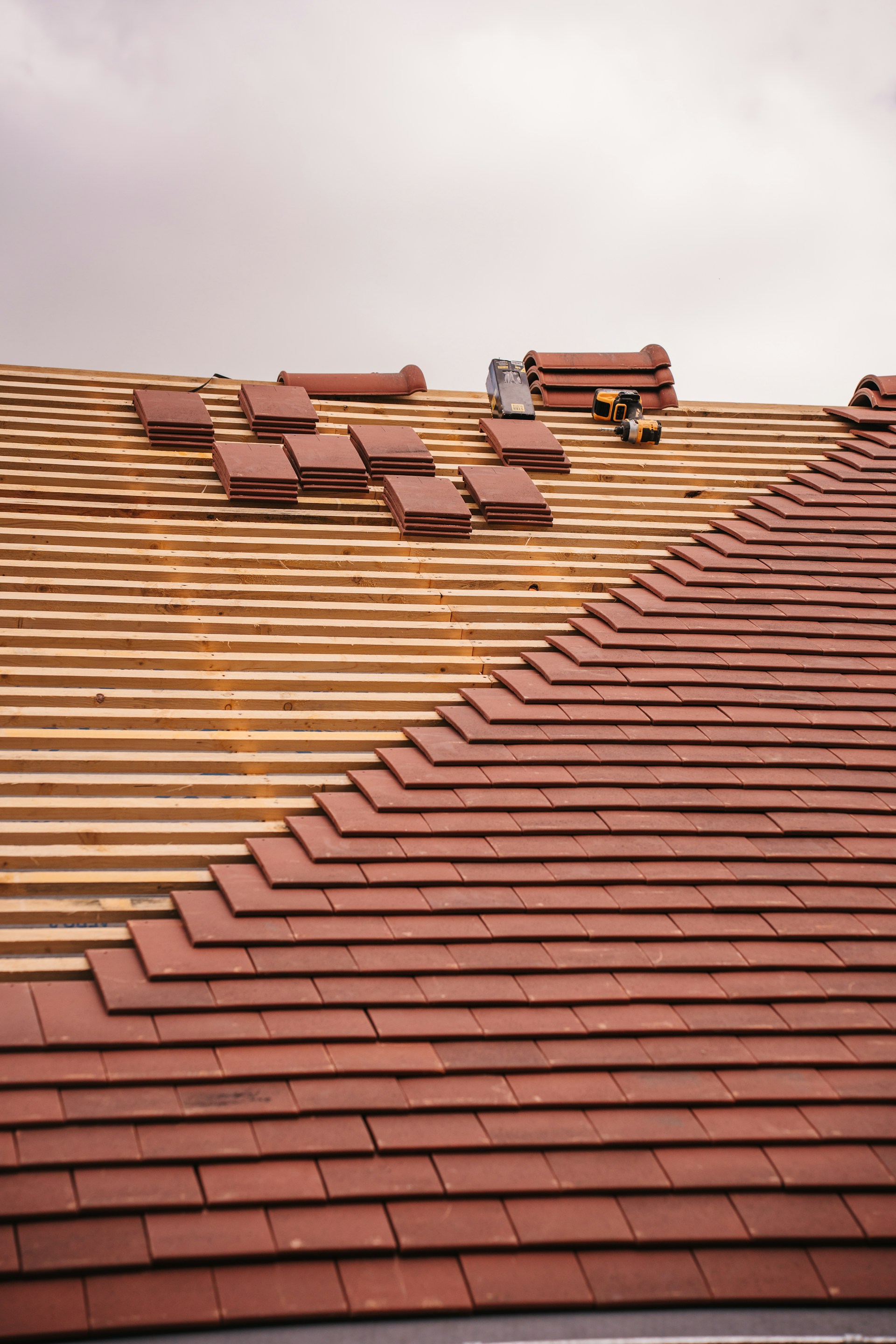 Roof tiles are being installed on a wooden frame.