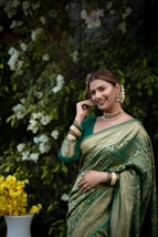 A woman poses gracefully in a green saree.