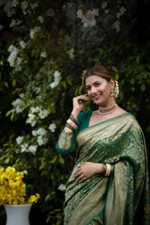 A woman poses gracefully in a green saree.