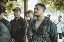 A group of men outdoors, looking towards something.