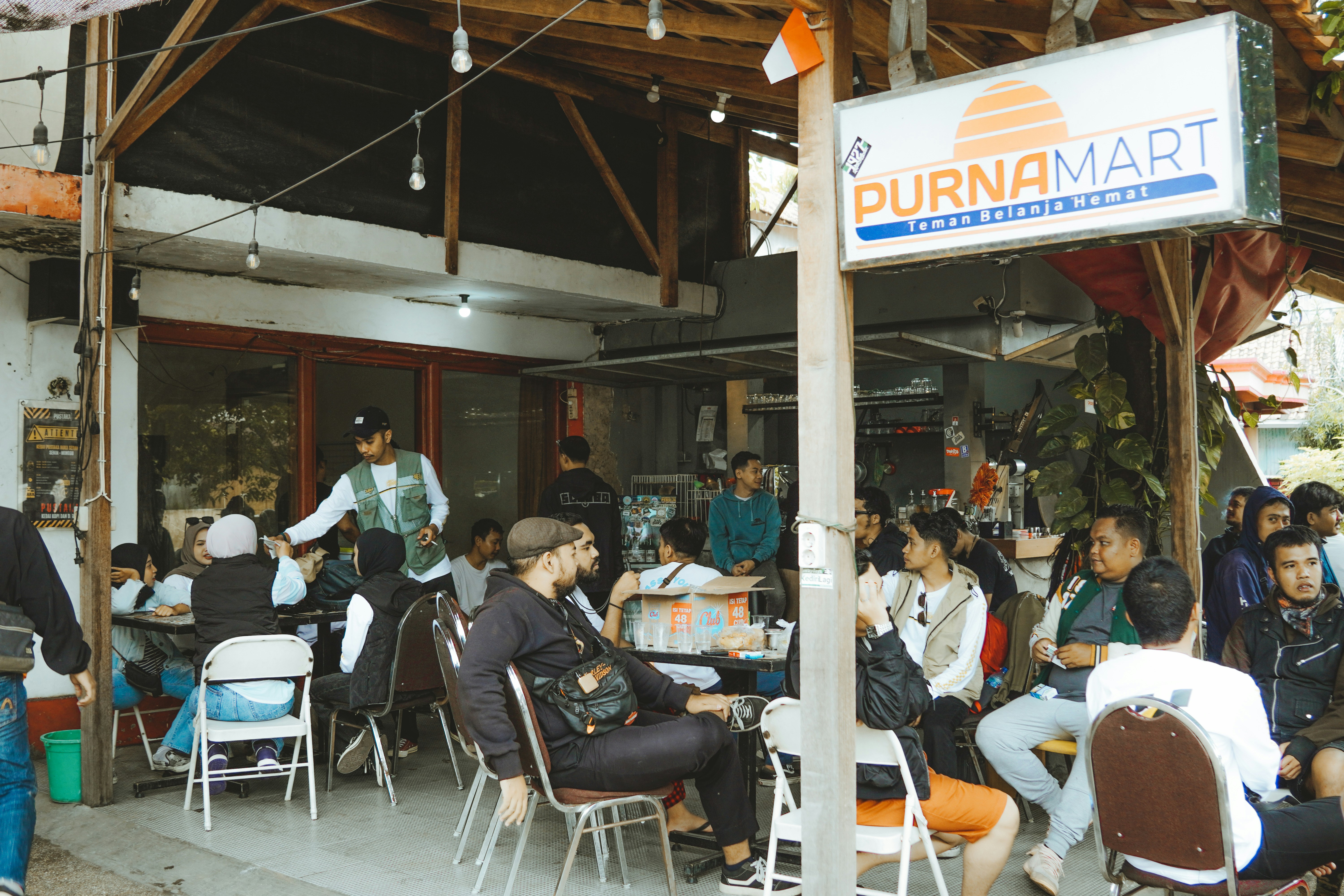 People socialize and eat outside a small cafe.