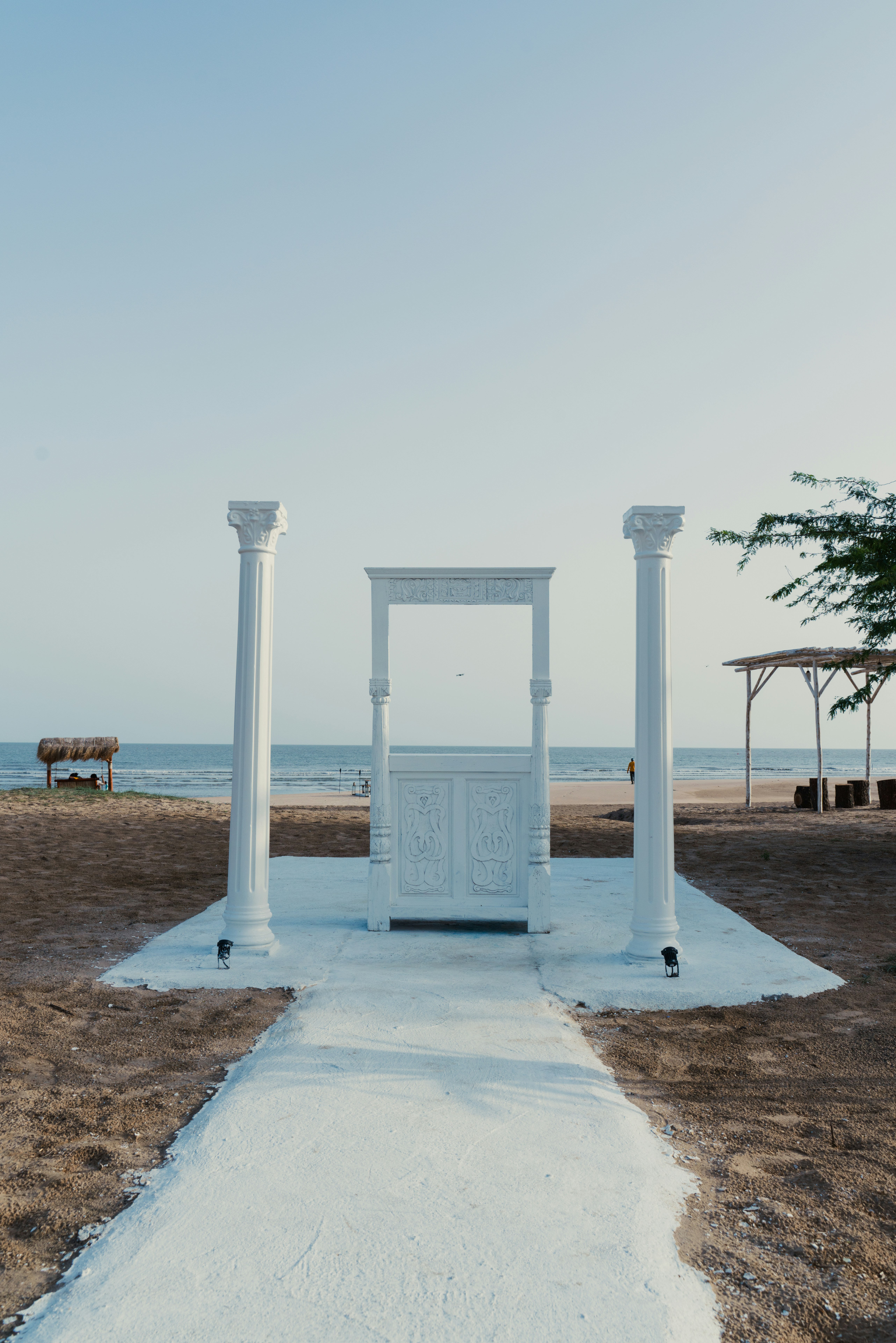 An ornate doorway stands on a sandy beach.