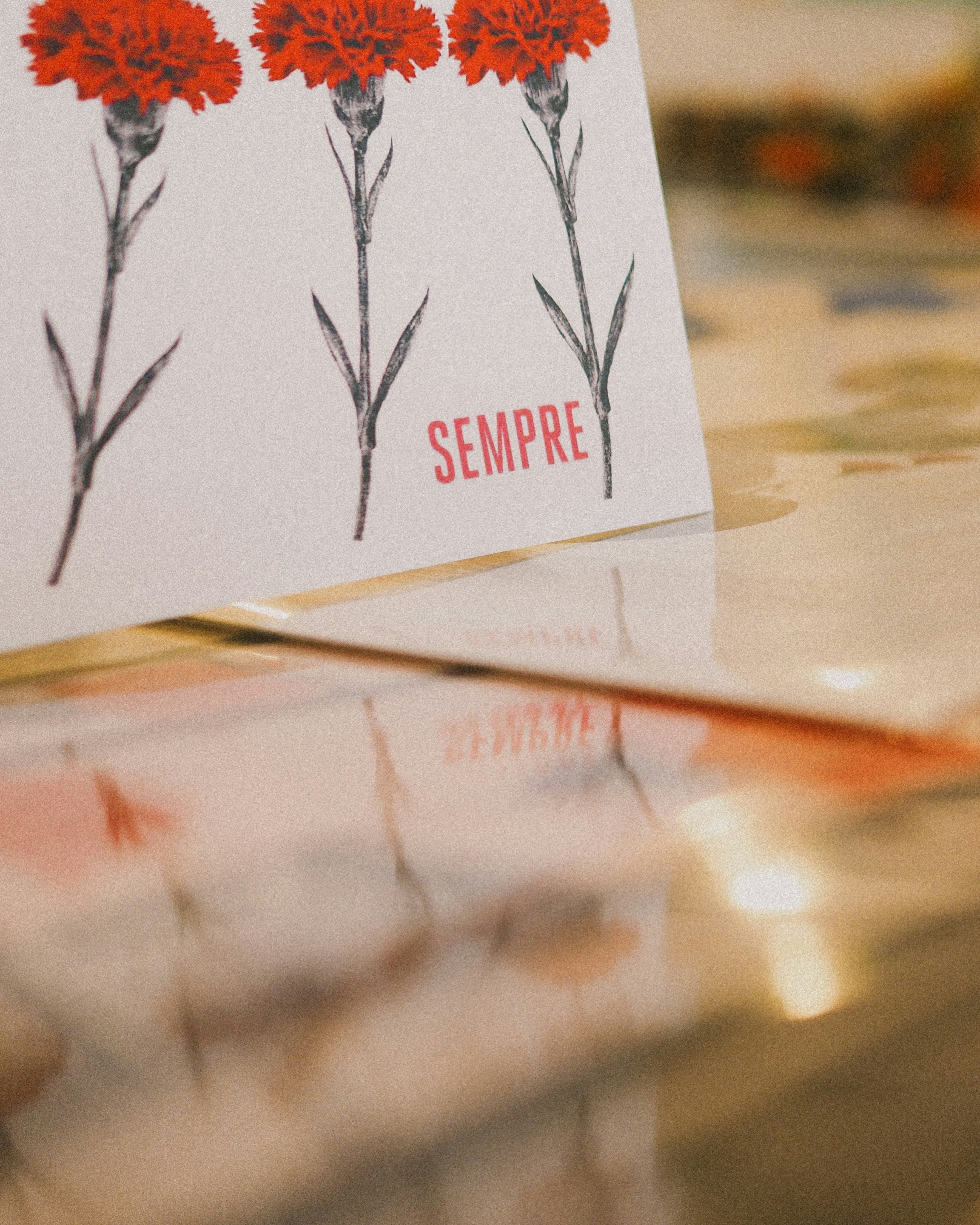 Three carnations with the word "sempre".