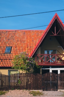 A house with a red roof and wooden fence.