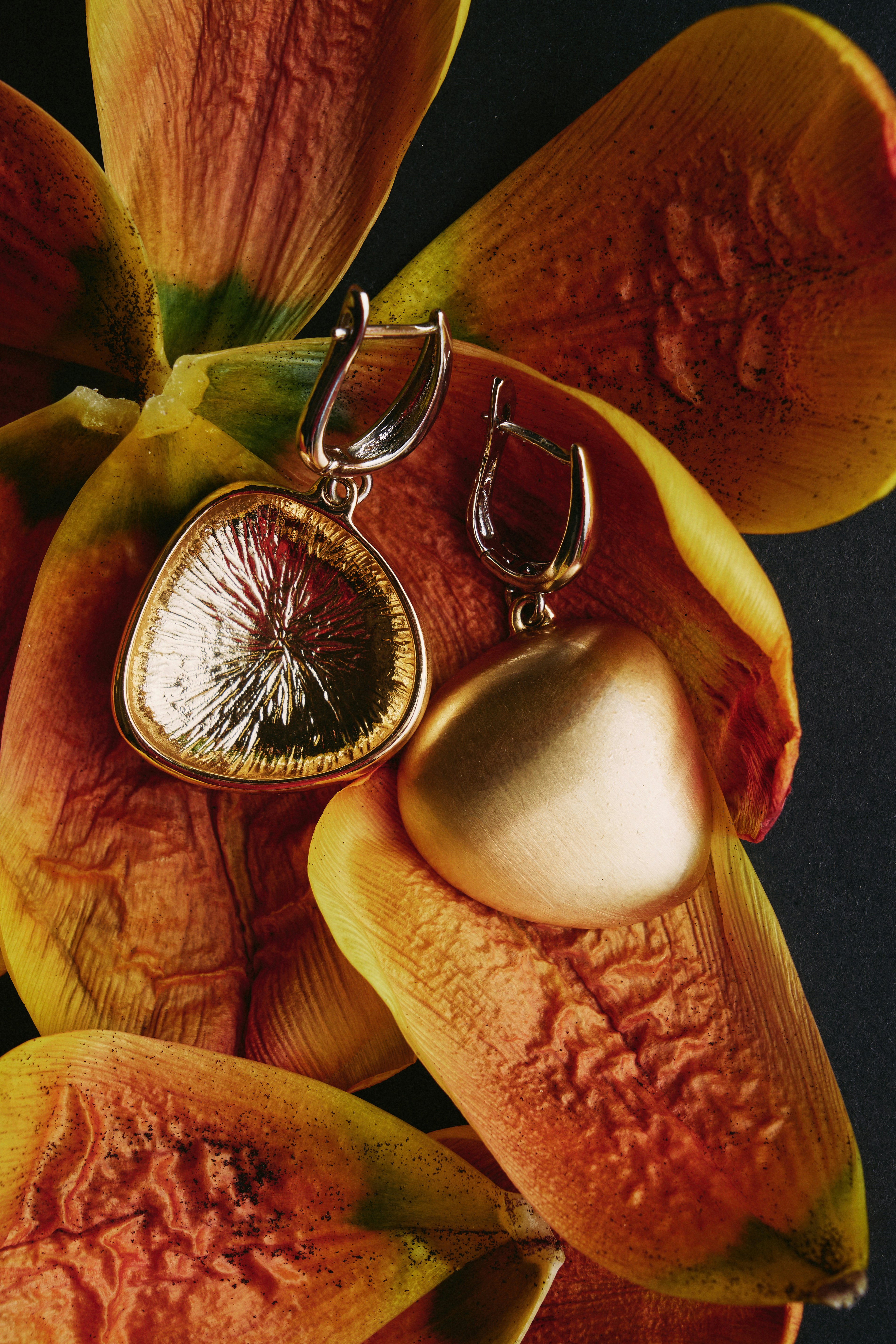 Elegant earrings rest on dried petals.
