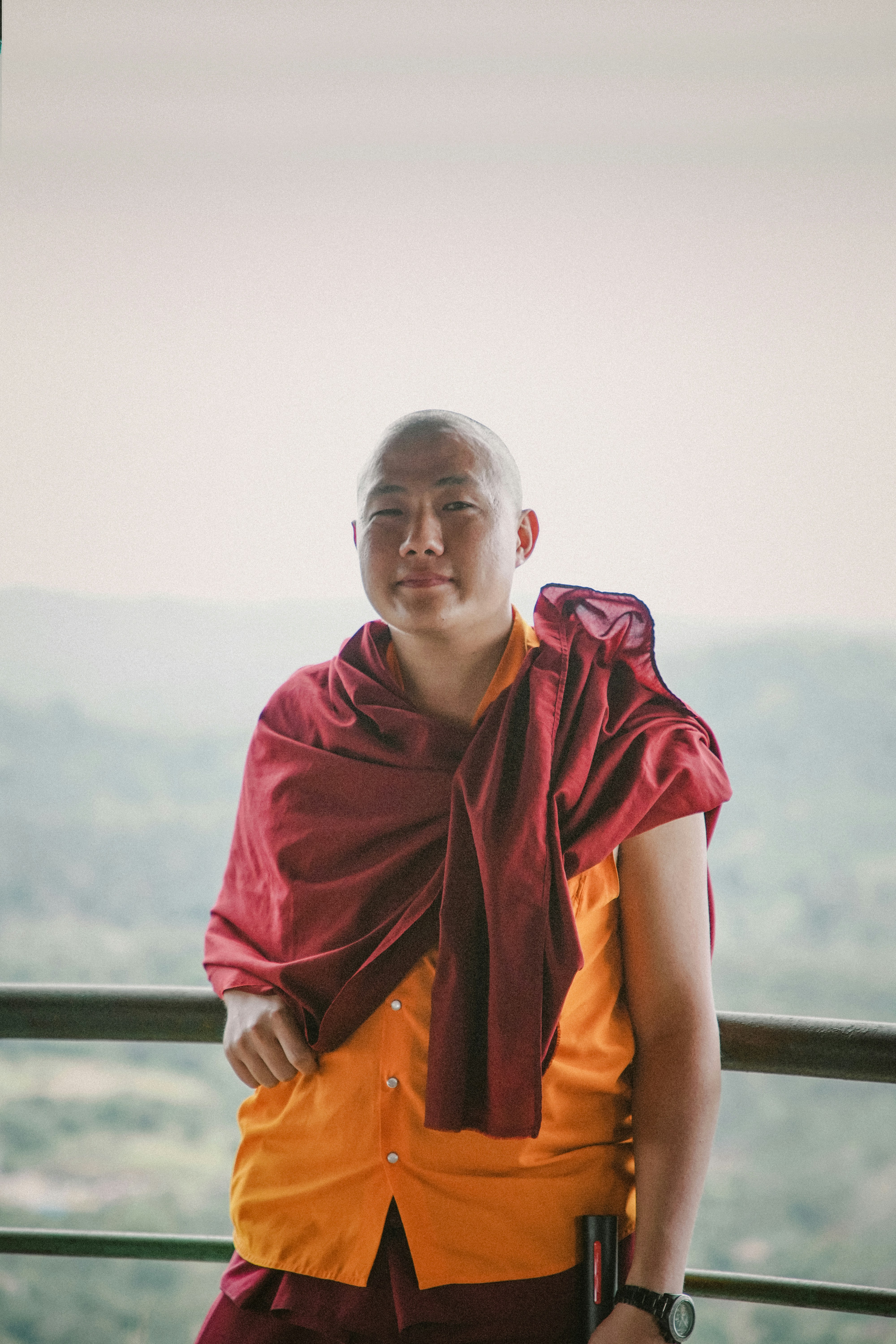 Monk steht draußen und lächelt in die Kamera.