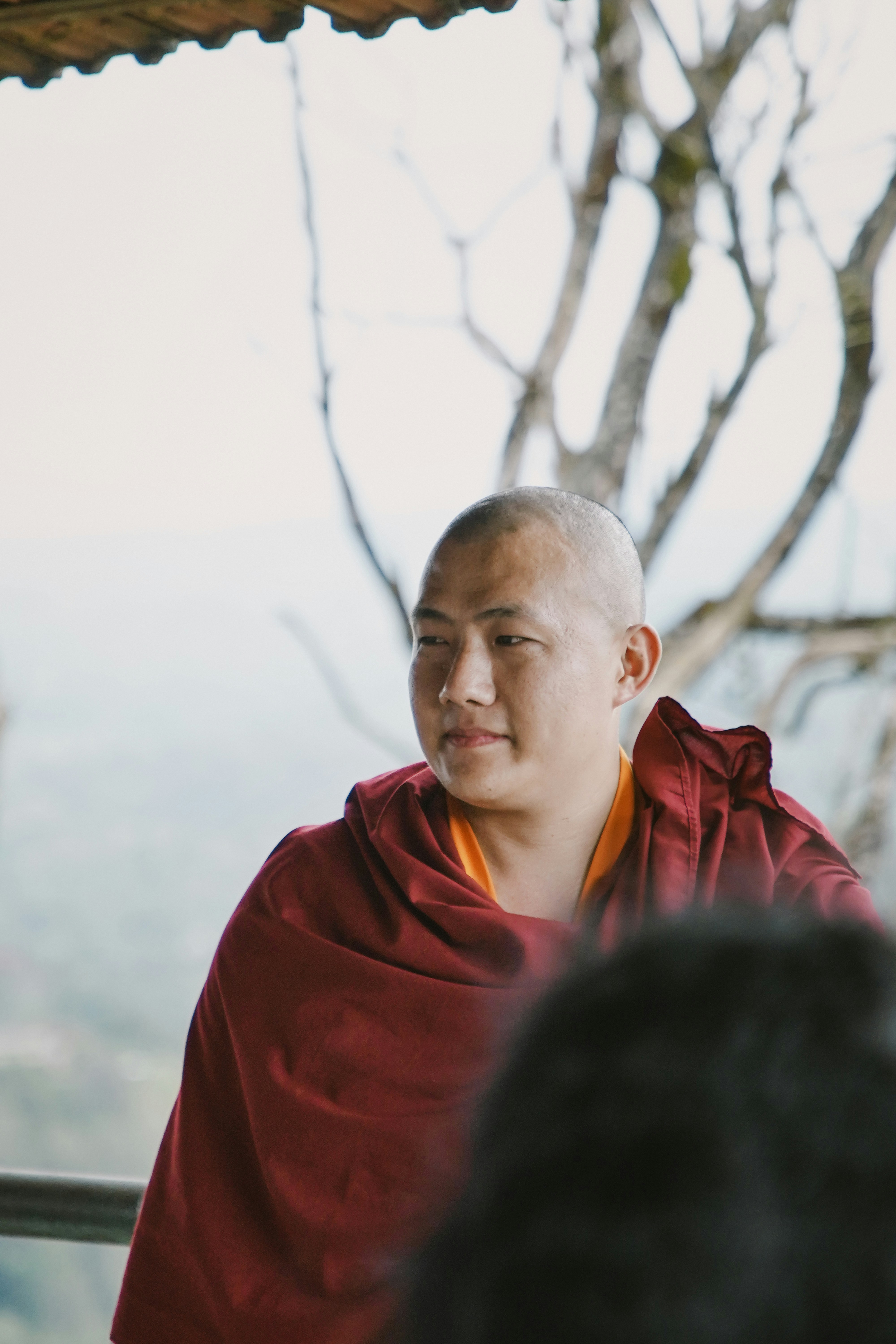 A buddhist monk is looking off in the distance.