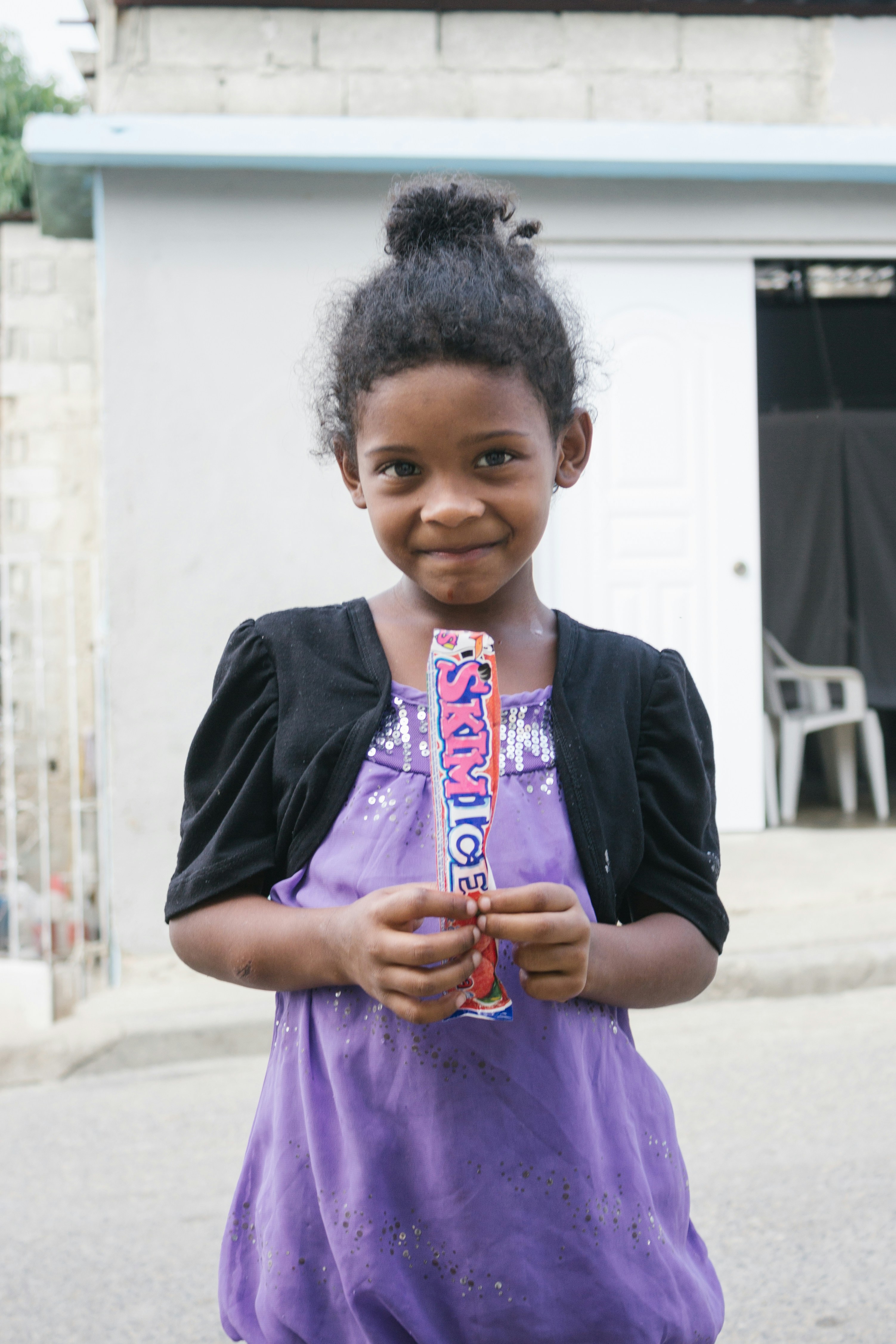 Girl holds candy and smiles at the camera.