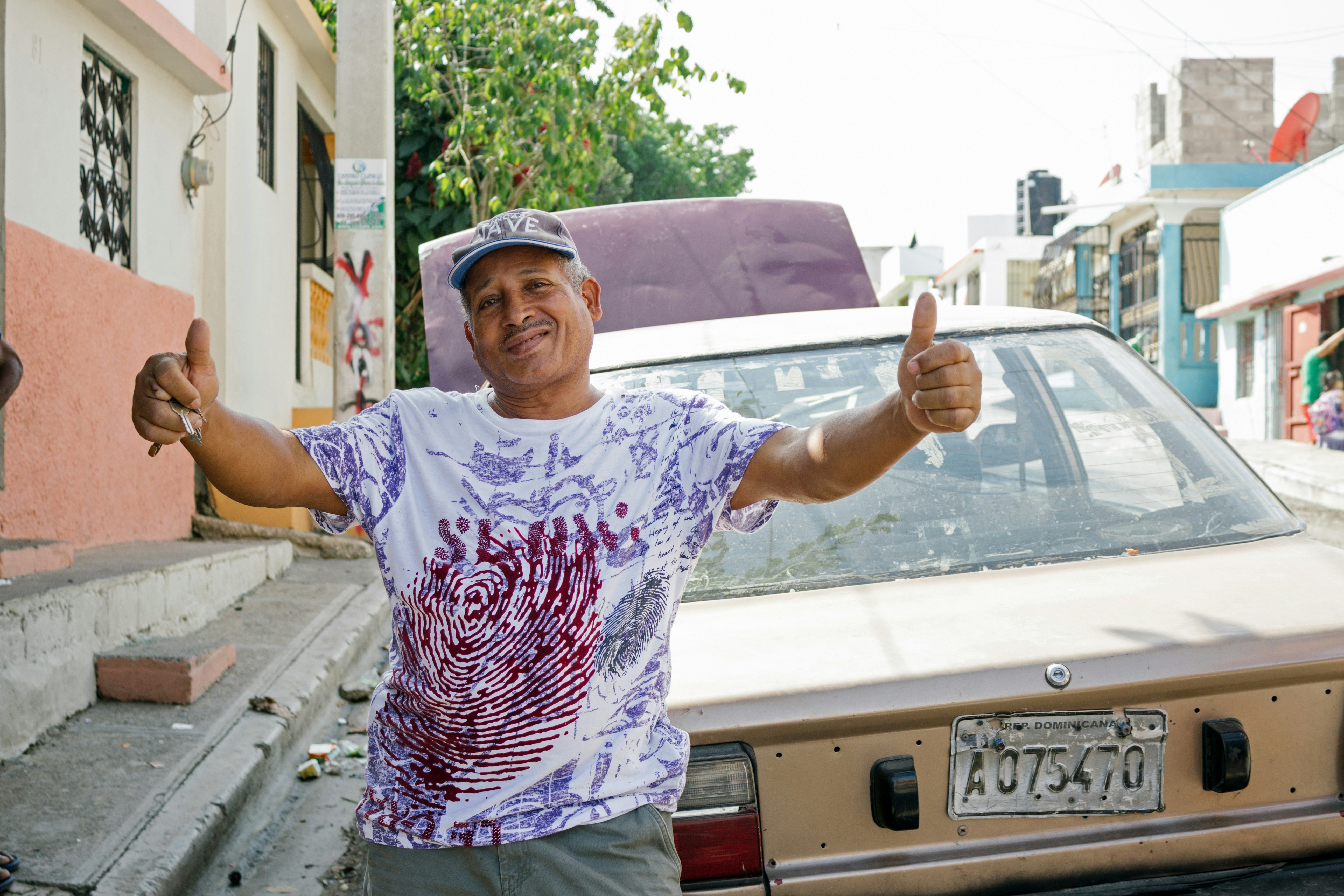 Man gives a thumbs up near a car.