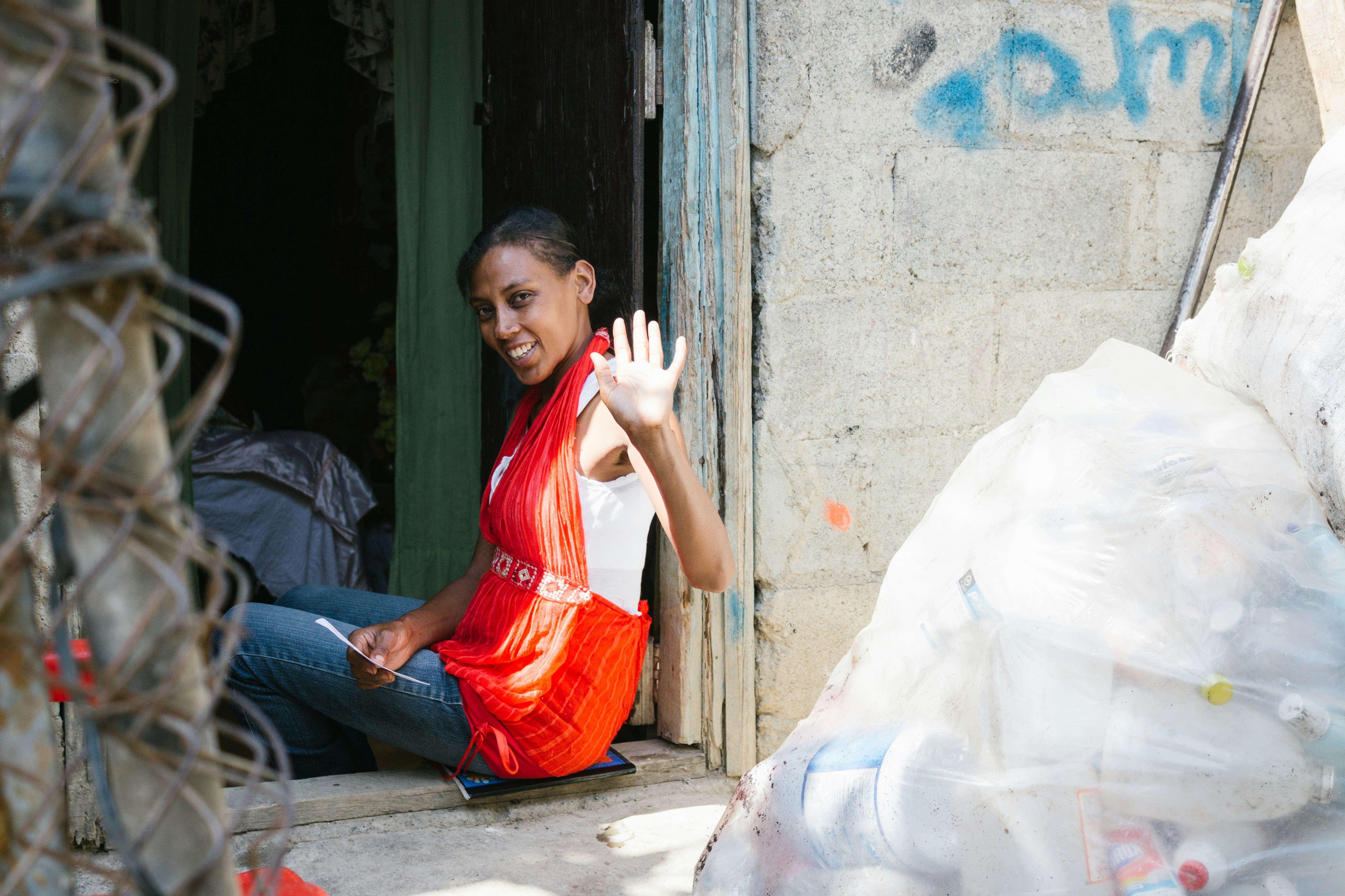 A woman waves from a doorway.
