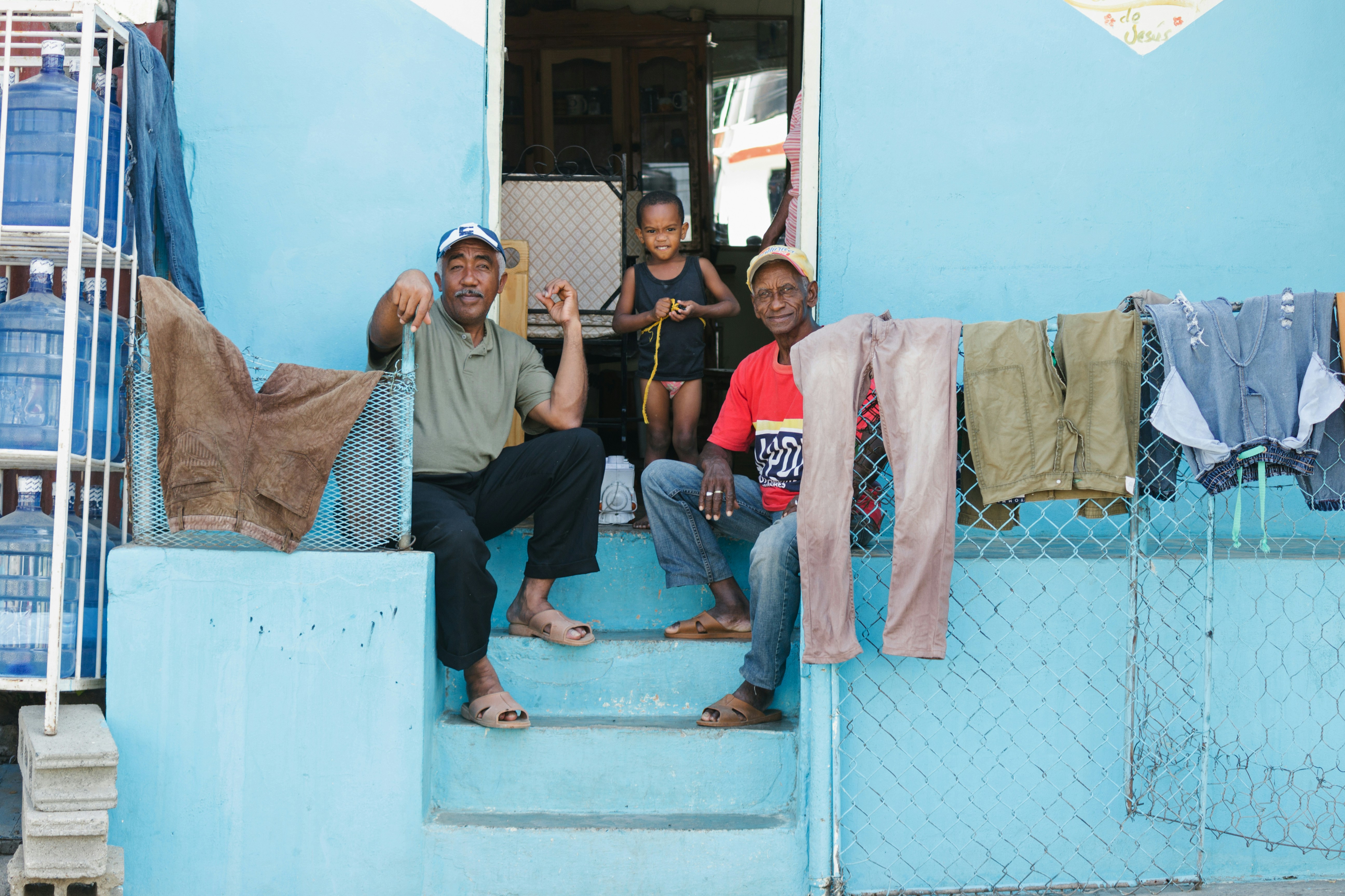 People relax on the porch of a blue house.